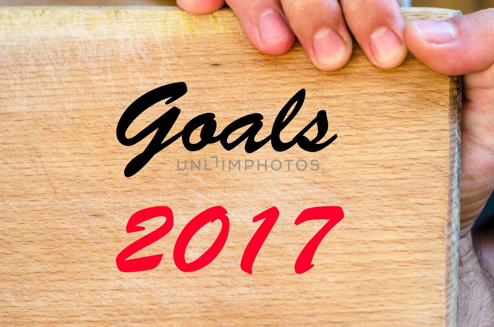 Human hand over wooden background and goals 2017 text concept