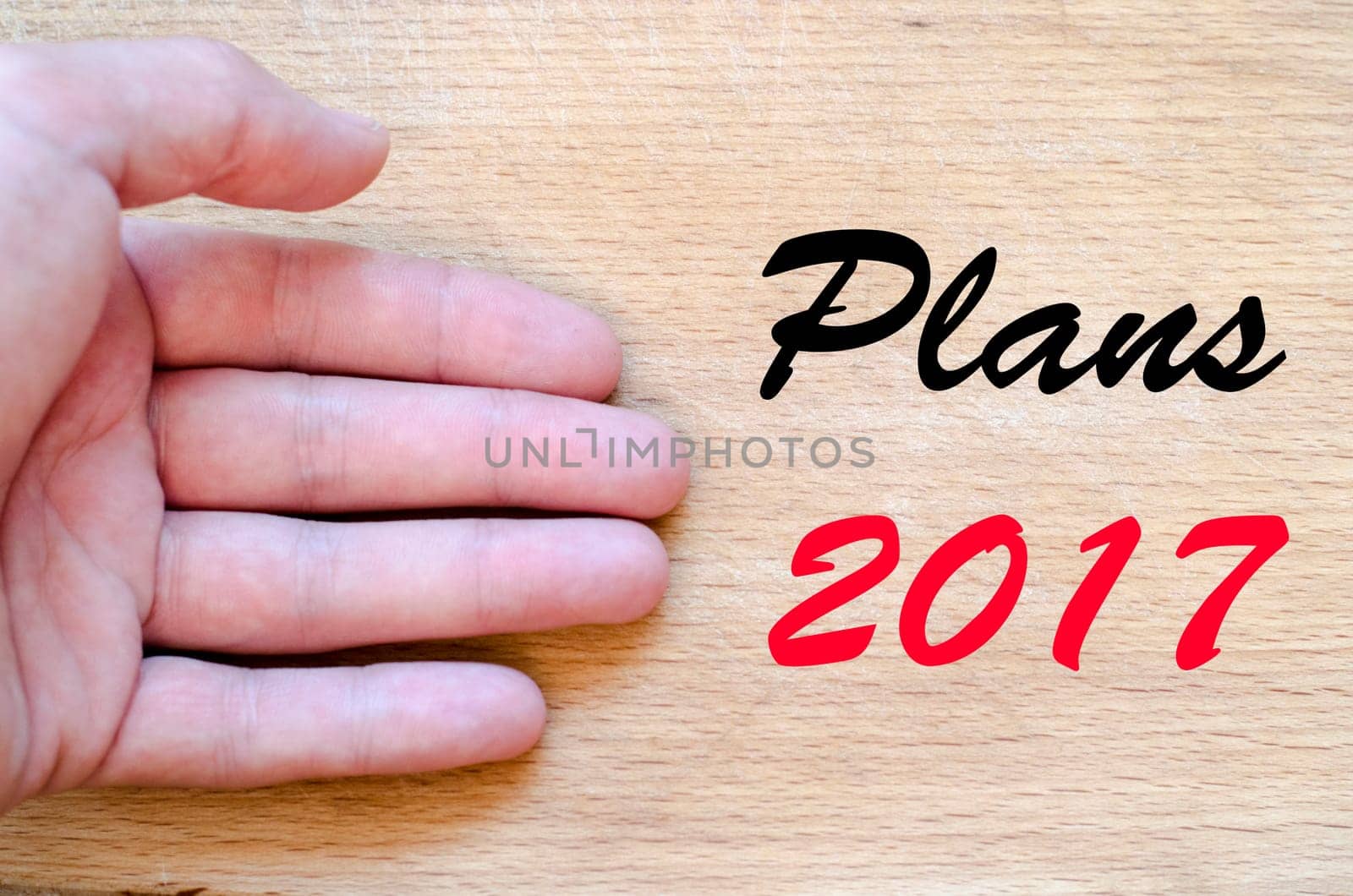 Human hand over wooden background and plans 2017 text concept