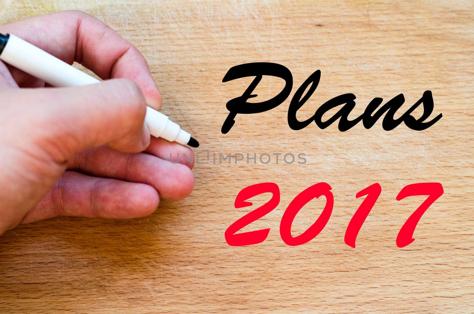 Human hand over wooden background and plans 2017 text concept