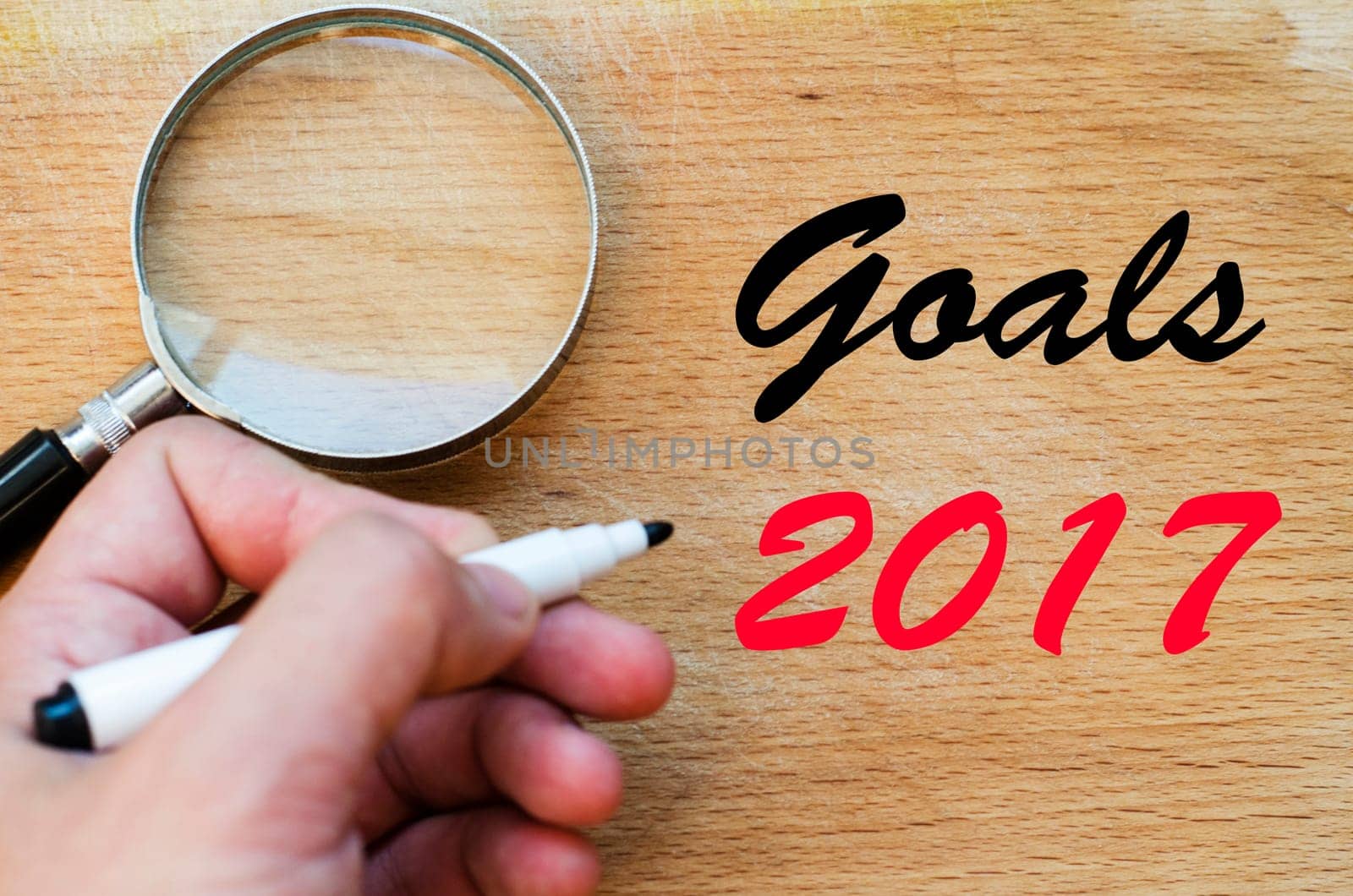 Human hand over wooden background and goals 2017 text concept