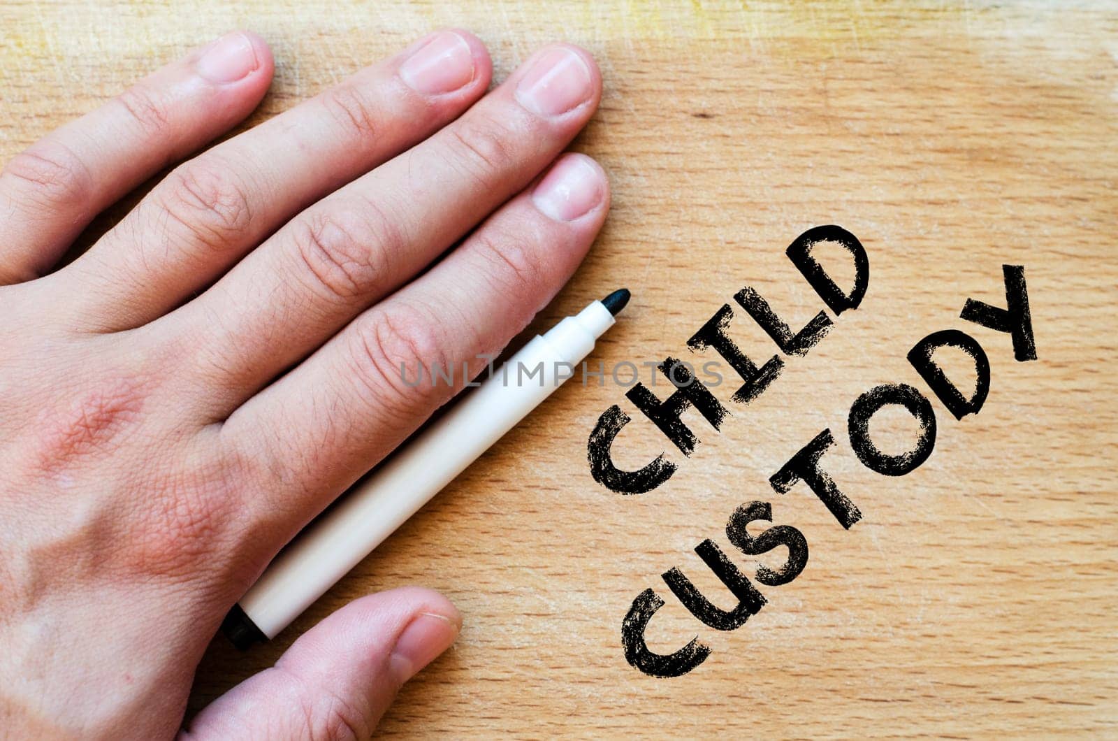 Human hand over wooden background and child custody text concept