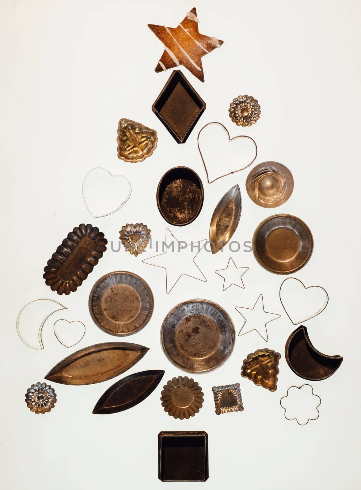 Christmas tree shape made from cookie cutters and food accessories on a white background.