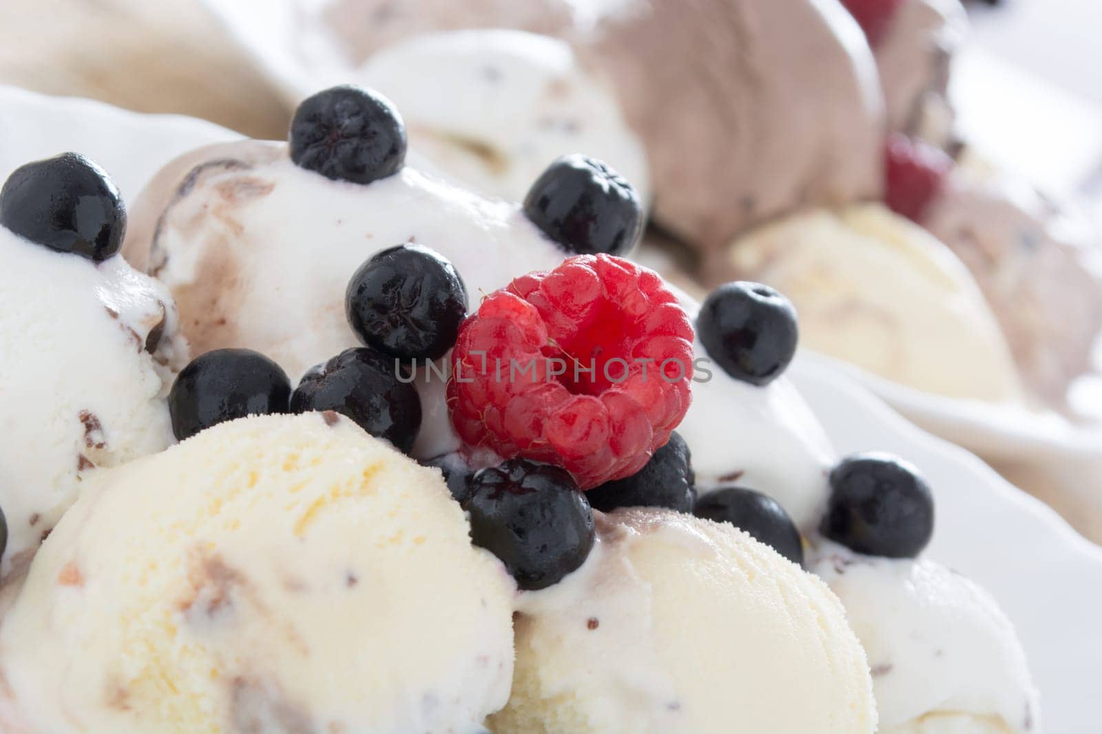 Scoops of chocolate ice cream in the white plate with raspberries and chokeberries
