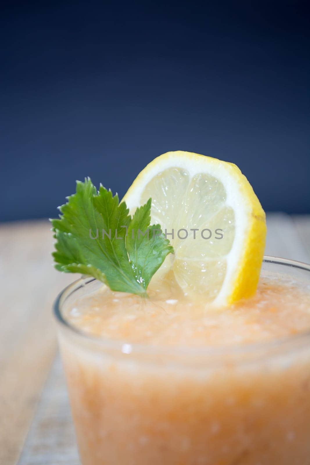 Fresh lemonade with ginger decorated with green celery leaves and lemon on the dark background