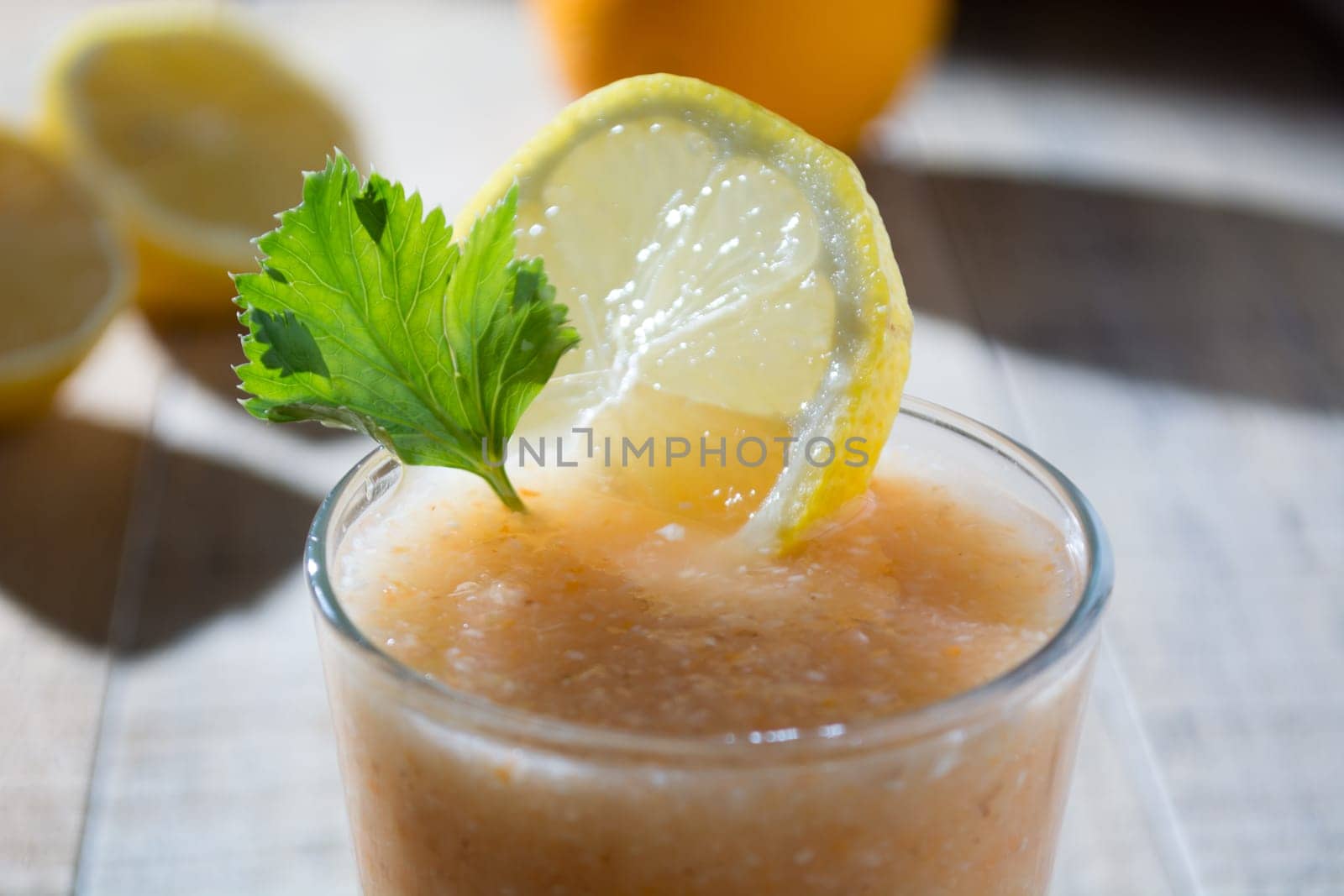 Fresh lemonade with ginger decorated with green celery leaves and lemon on the dark background