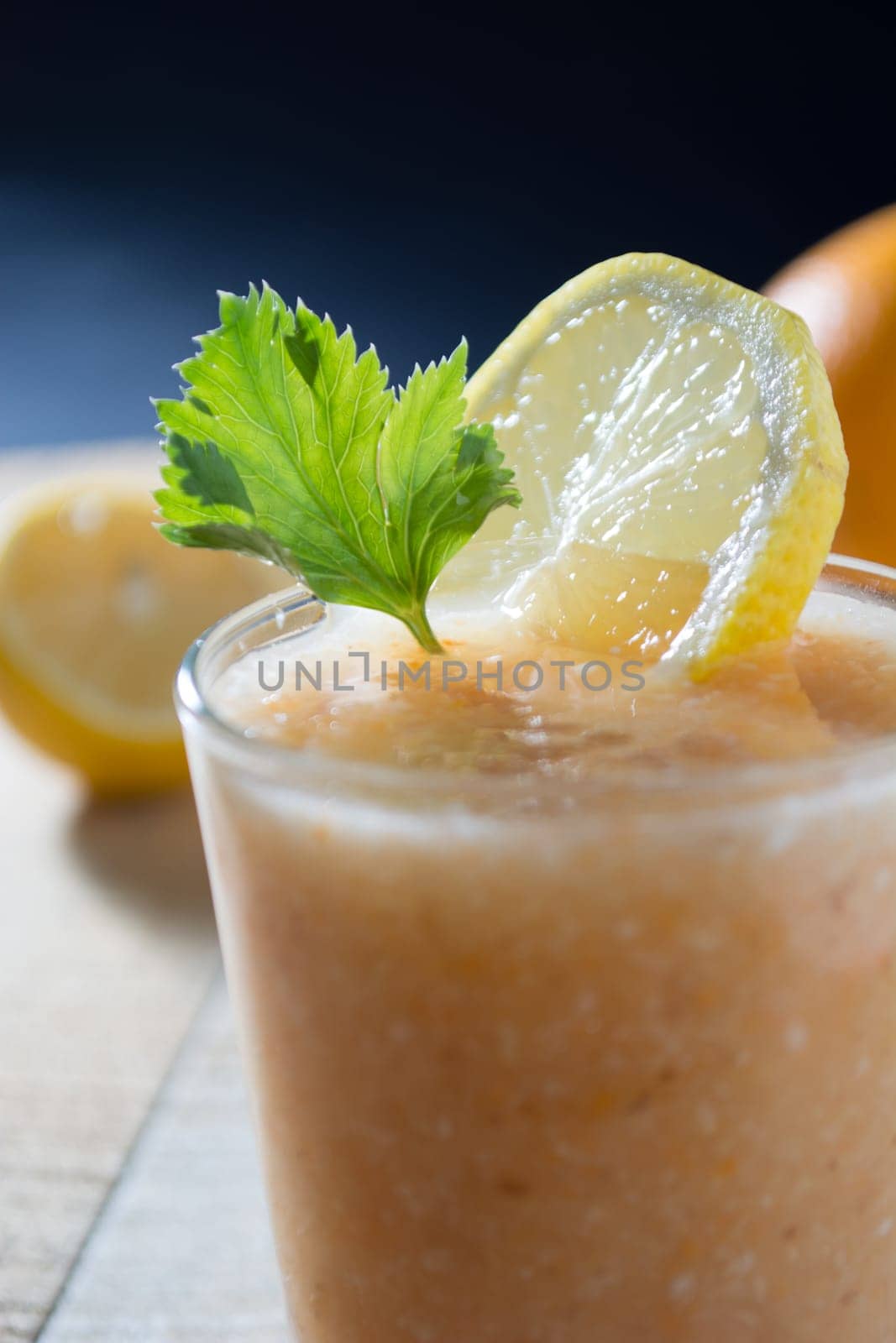 Fresh lemonade with ginger decorated with green celery leaves and lemon on the dark background
