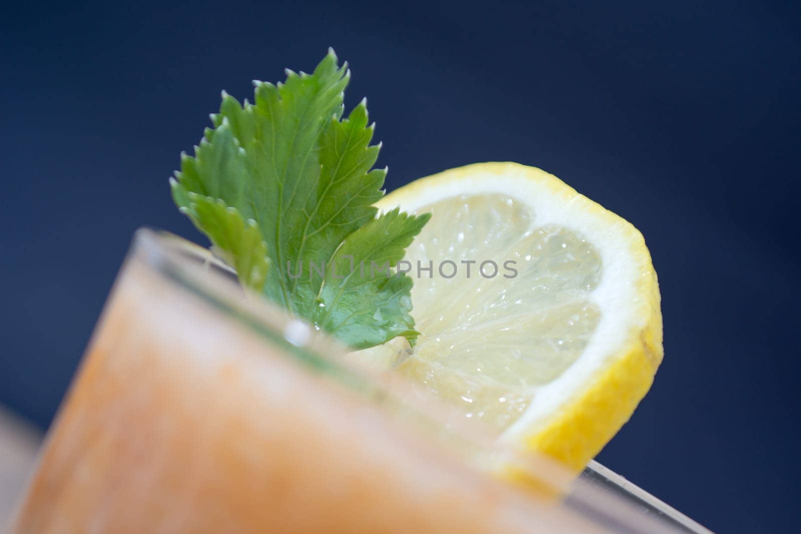 Fresh lemonade with ginger decorated with green celery leaves and lemon on the dark background