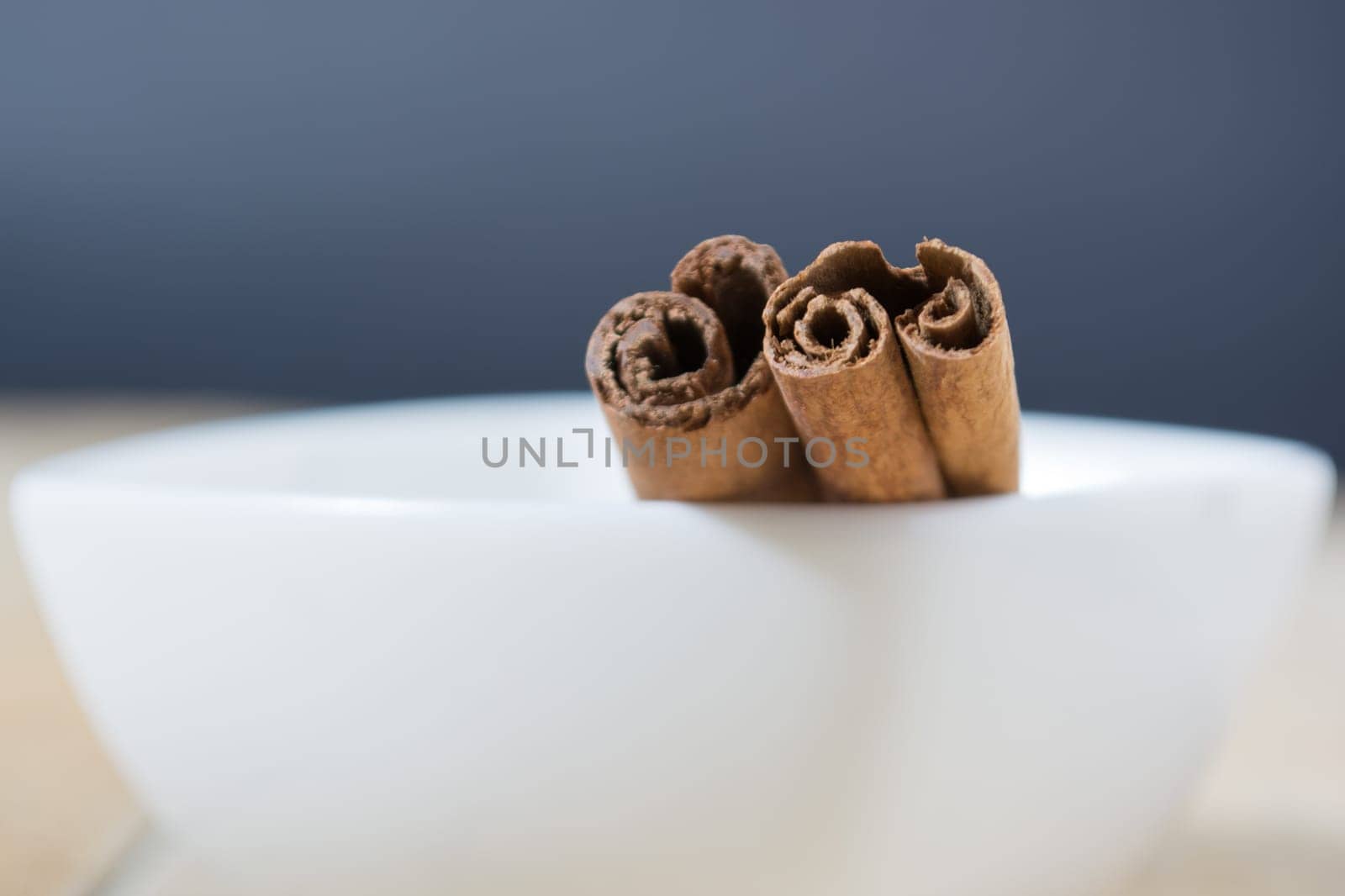 Close up of cinnamon sticks in a white bowl shot with shallow depth of field