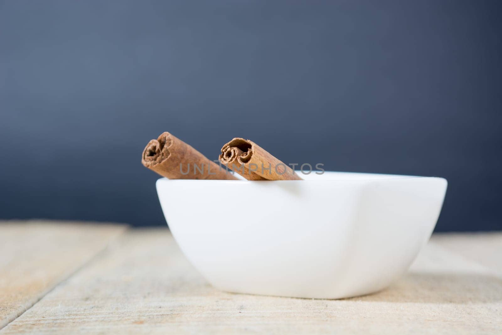 Close up of cinnamon sticks in a white bowl shot with shallow depth of field