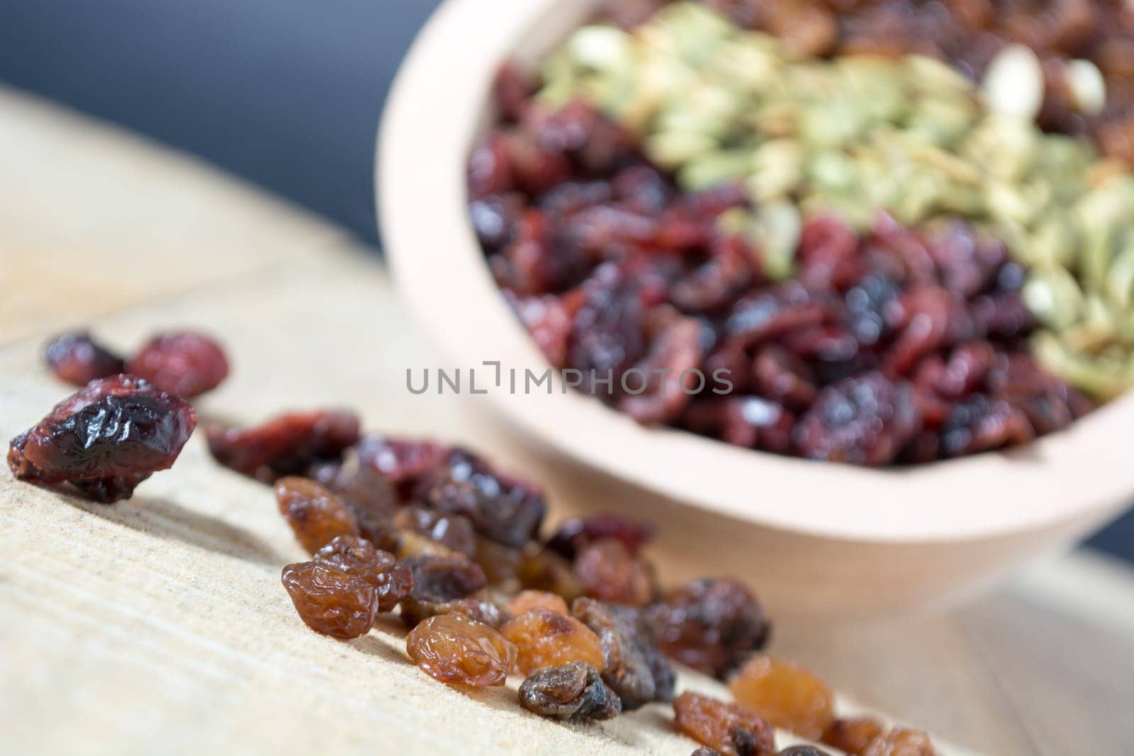 Bowl full with dry fruits and pumpkin seeds on the wooden table, shoot with selective focus