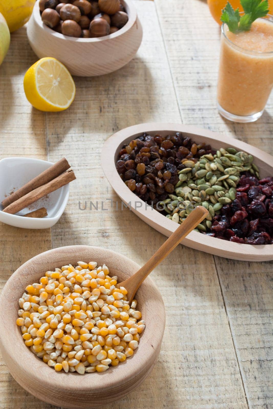 Wooden table with dry fruits and various seeds, cinnamon and other ingredients for healthy meal
