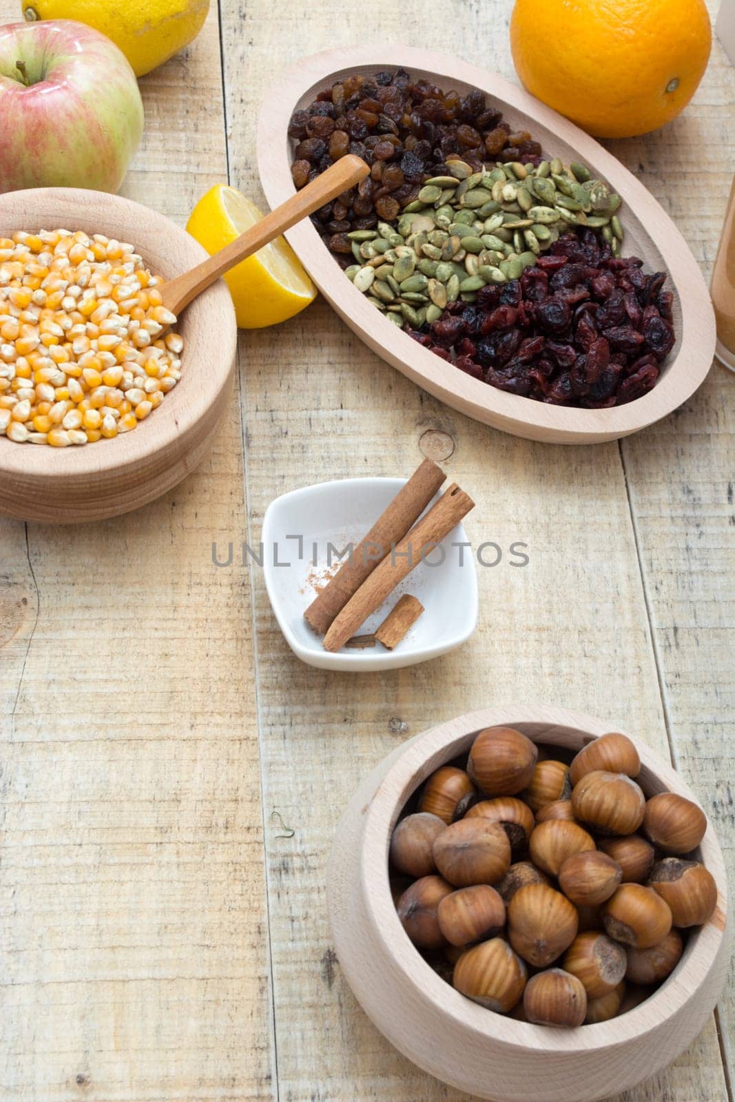 Wooden table with dry fruits and various seeds, cinnamon and other ingredients for healthy meal