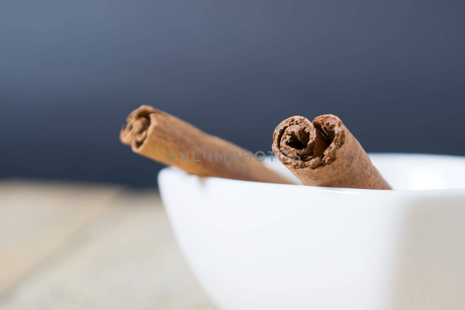 Close up of cinnamon sticks in a white bowl shot with shallow depth of field