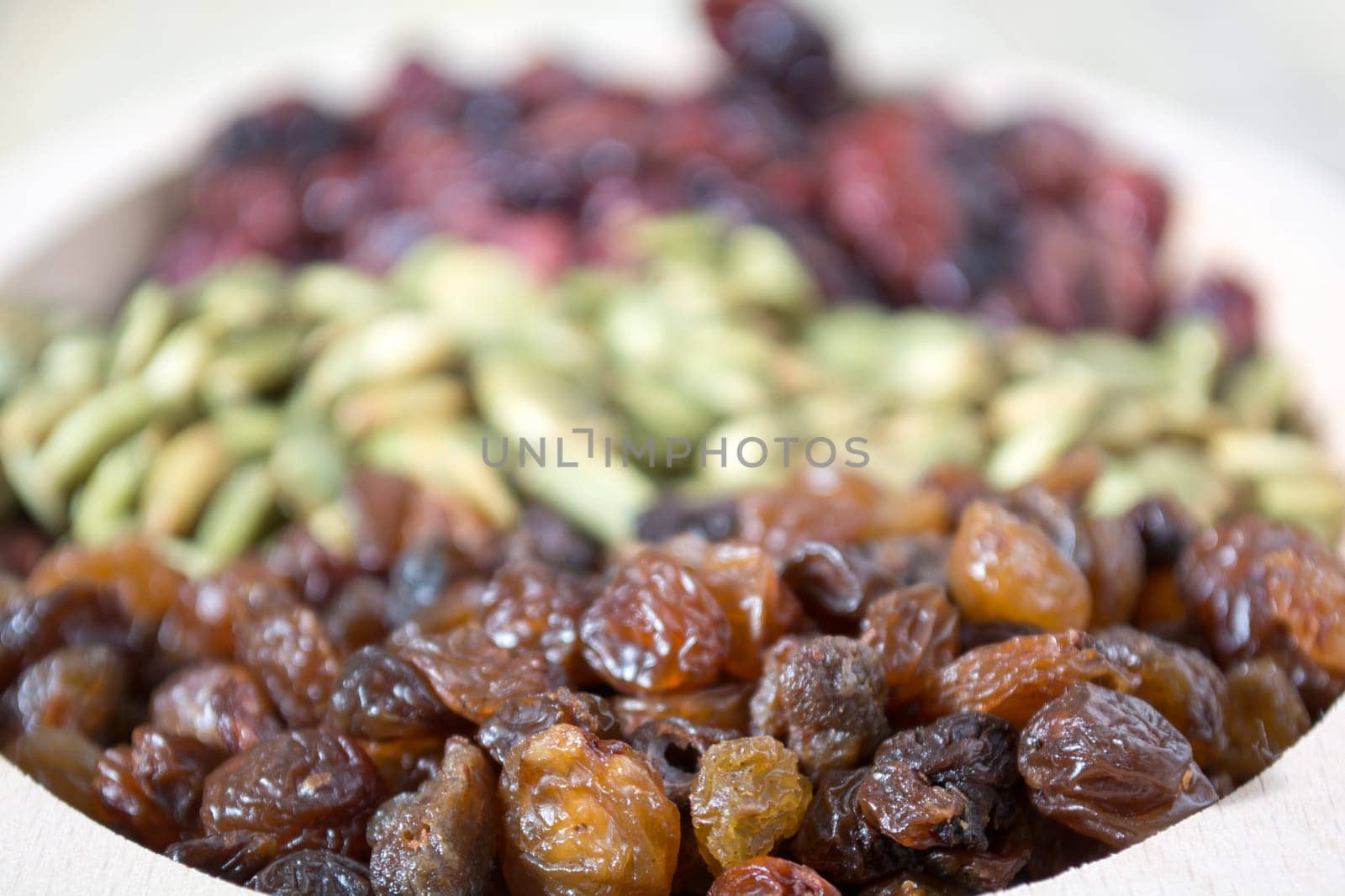 Bowl full with dry fruits and pumpkin seeds on the wooden table, shoot with selective focus