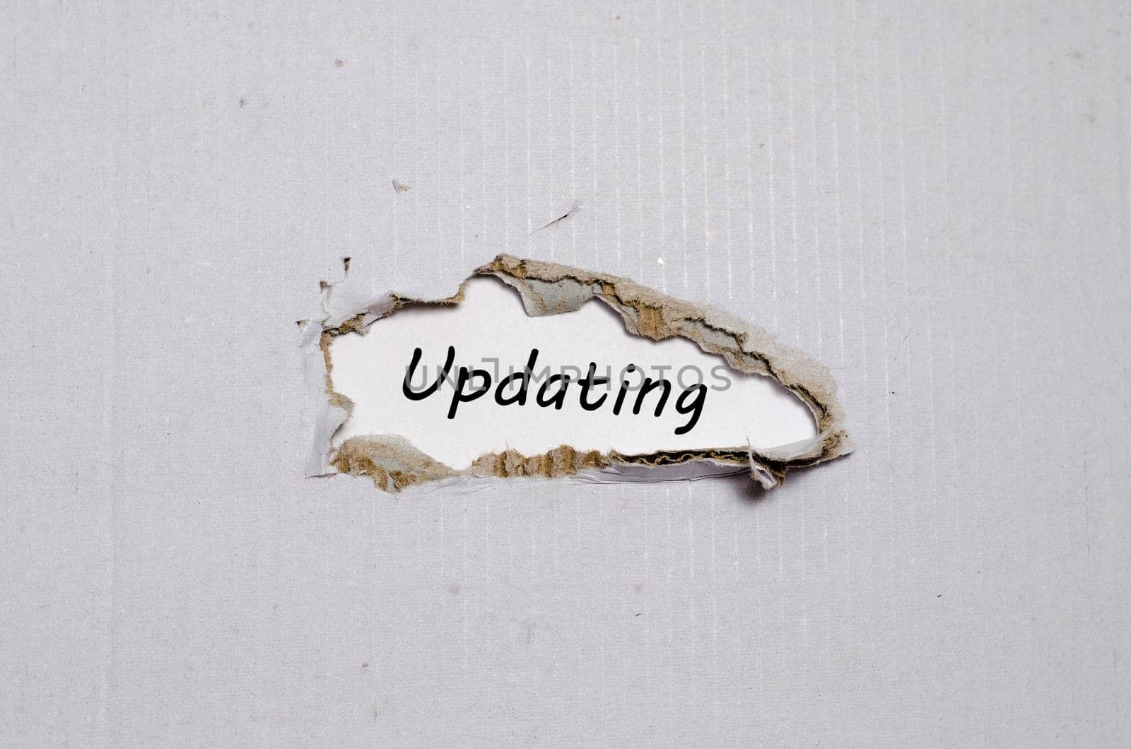 The word updating appearing behind torn paper