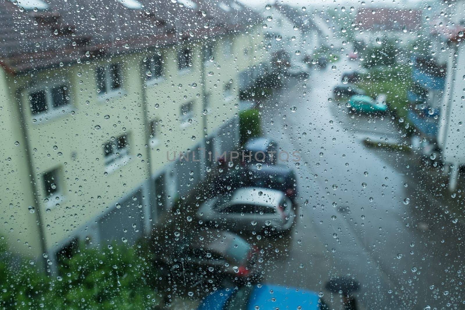 Raindrops on a window overlooking a street and houses