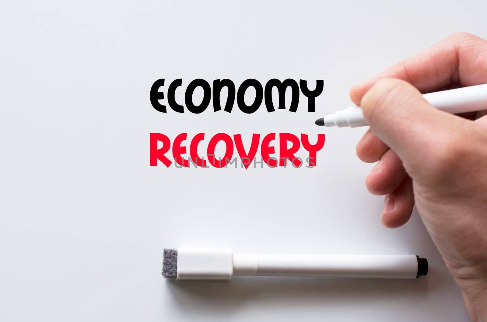 Human hand writing economy recovery on whiteboard