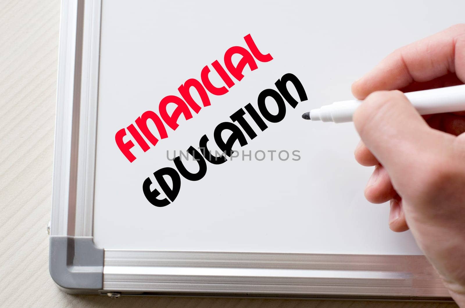 Human hand writing financial education on whiteboard