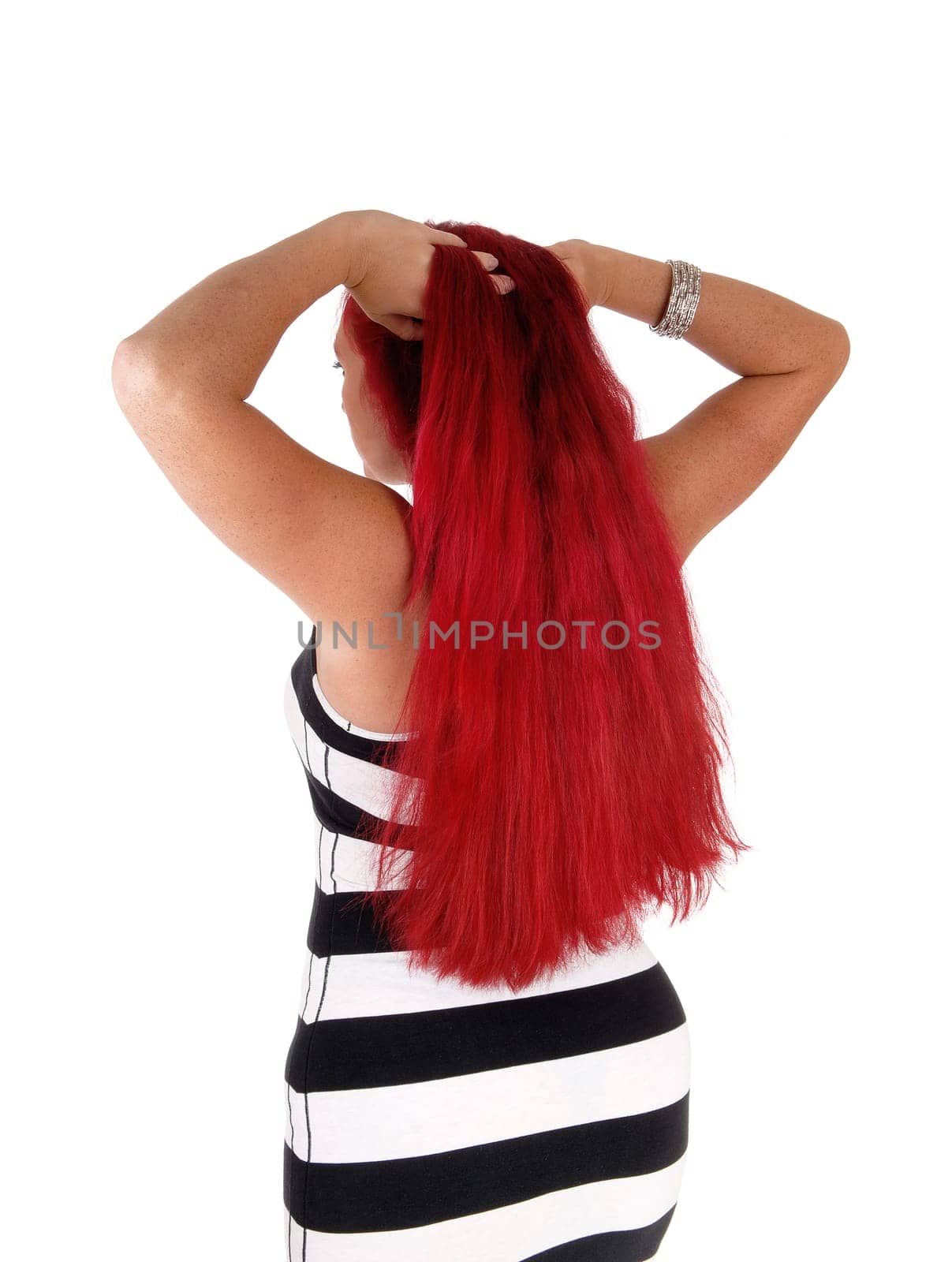 A closeup image of a woman with long red hair and a black and white.striped dress, standing from the back, isolated for white background..