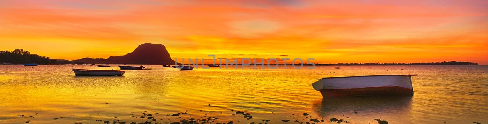 Fishing boat at sunset time. Le Morn Brabant on background. Mauritius. Panorama