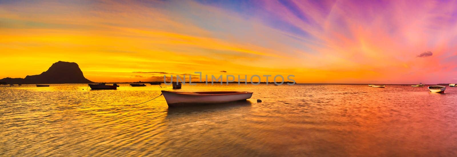 Fishing boat at sunset time. Le Morn Brabant on background. Mauritius. Panorama
