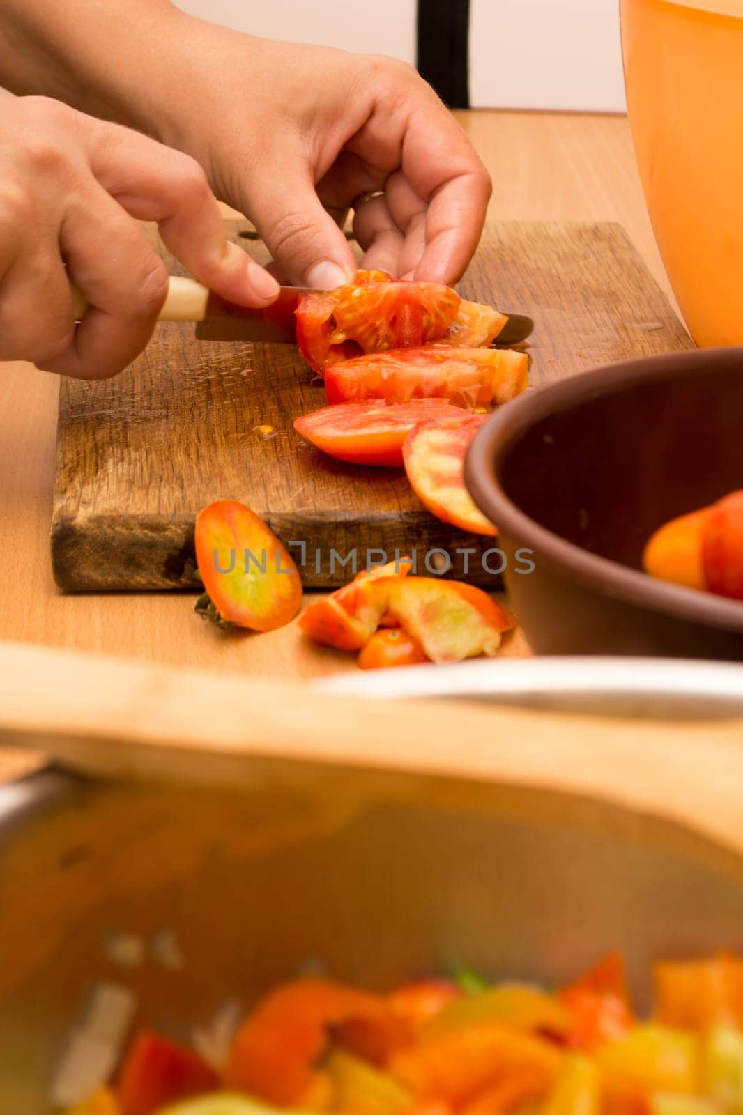 Cutting and chopping  tomato on a wooden plate. Preparing it for a salad
