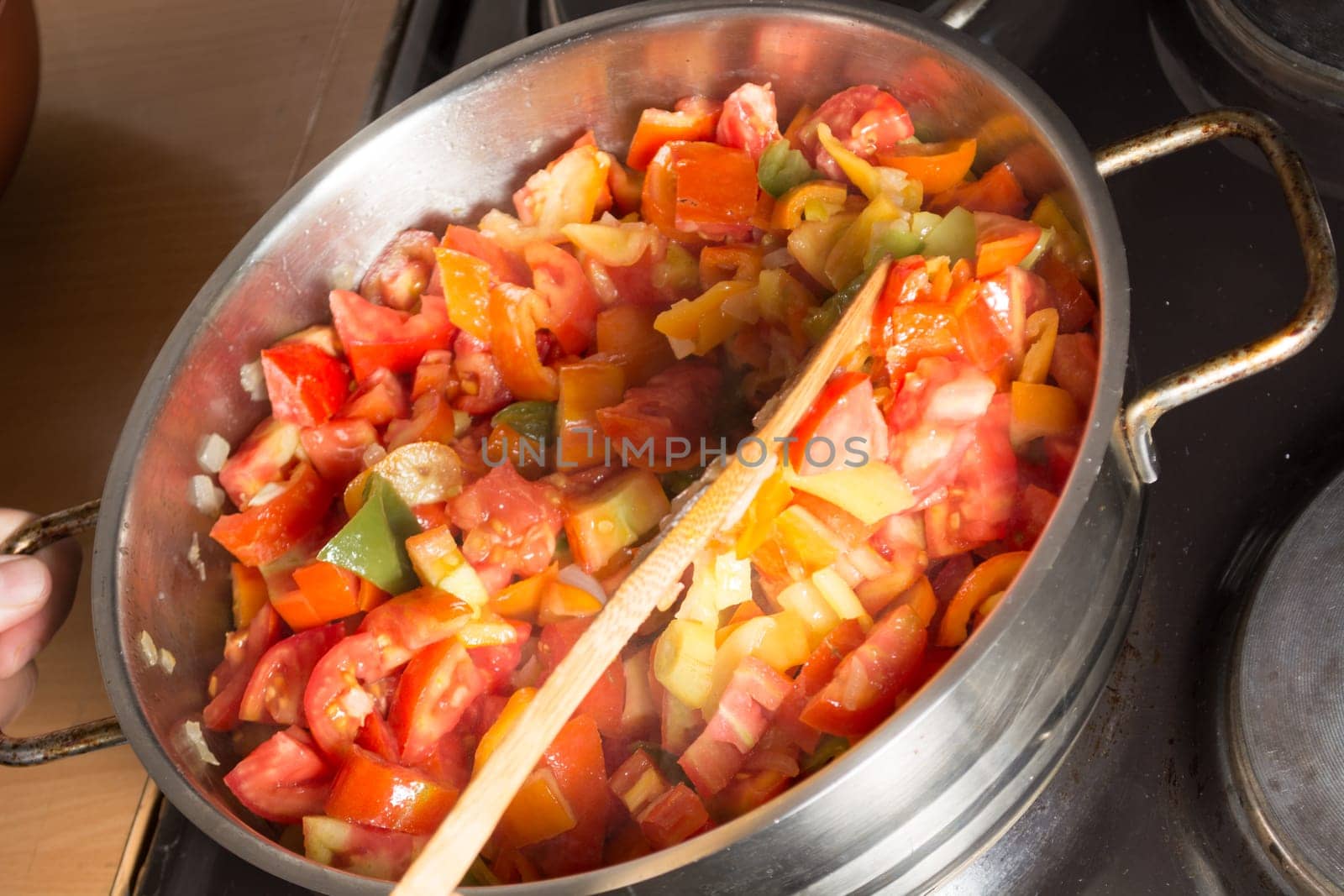 Cooking stew with fresh vegetables in a pot. Mixing it with mixing spoon