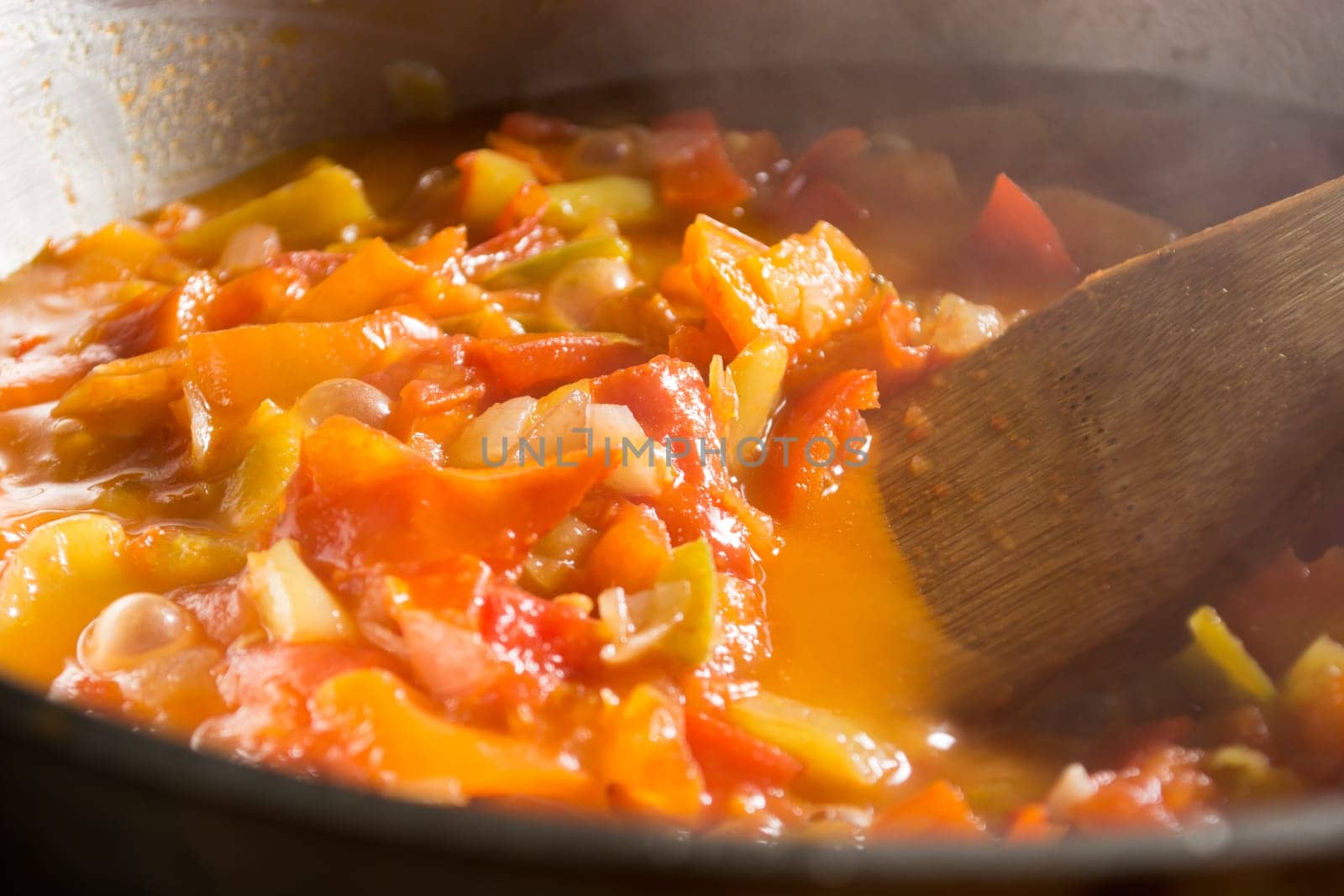 Cooking stew with fresh vegetables in a pot. Mixing it with mixing spoon