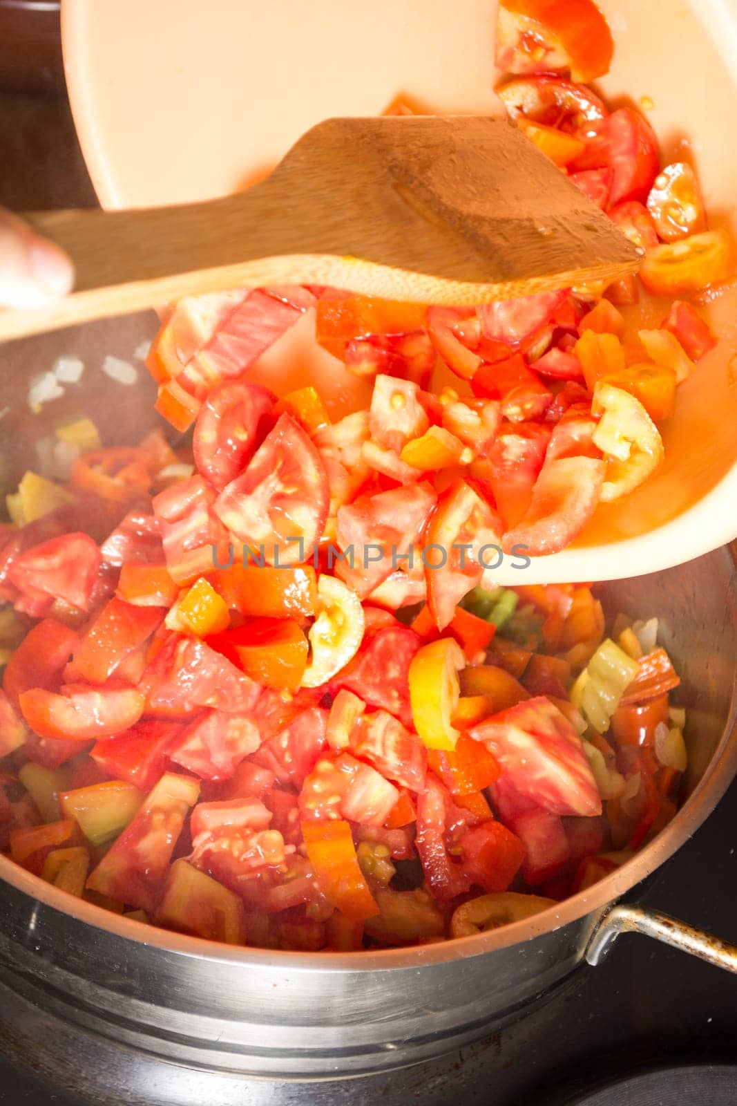 Cooking stew with fresh vegetables in a pot. Mixing it with mixing spoon