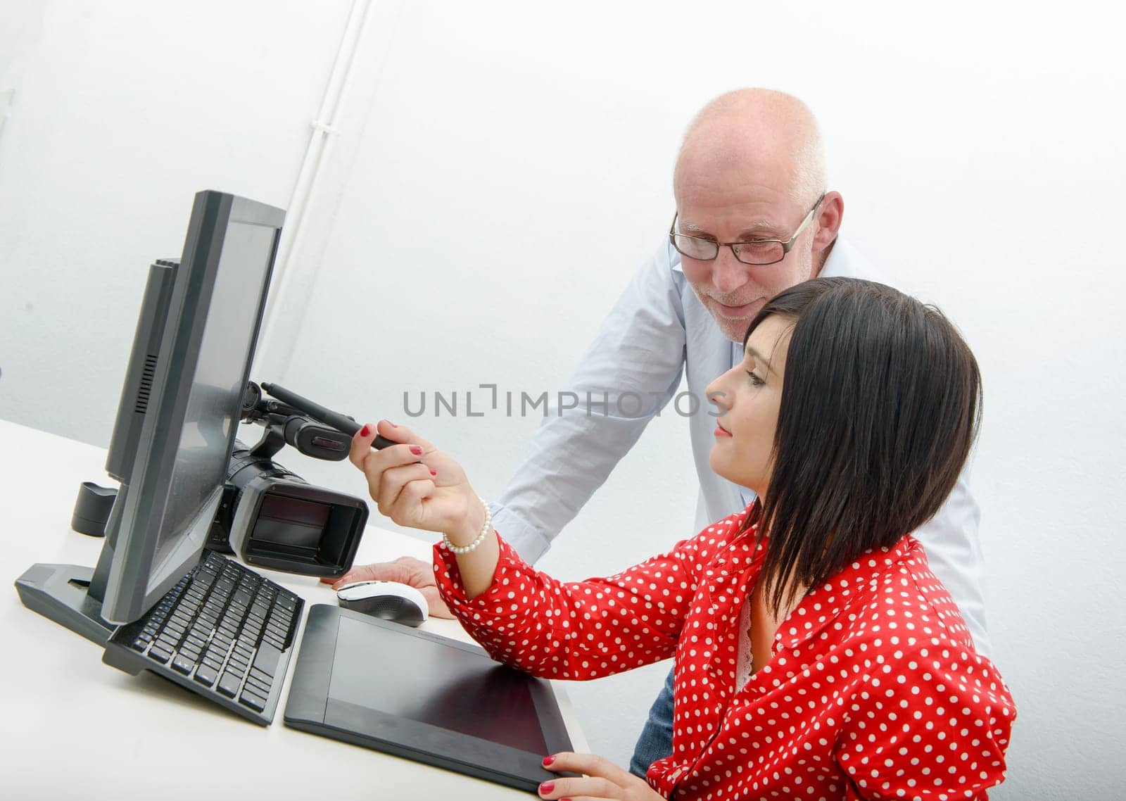 Young female designer and mature man using graphics tablet while working with computer
