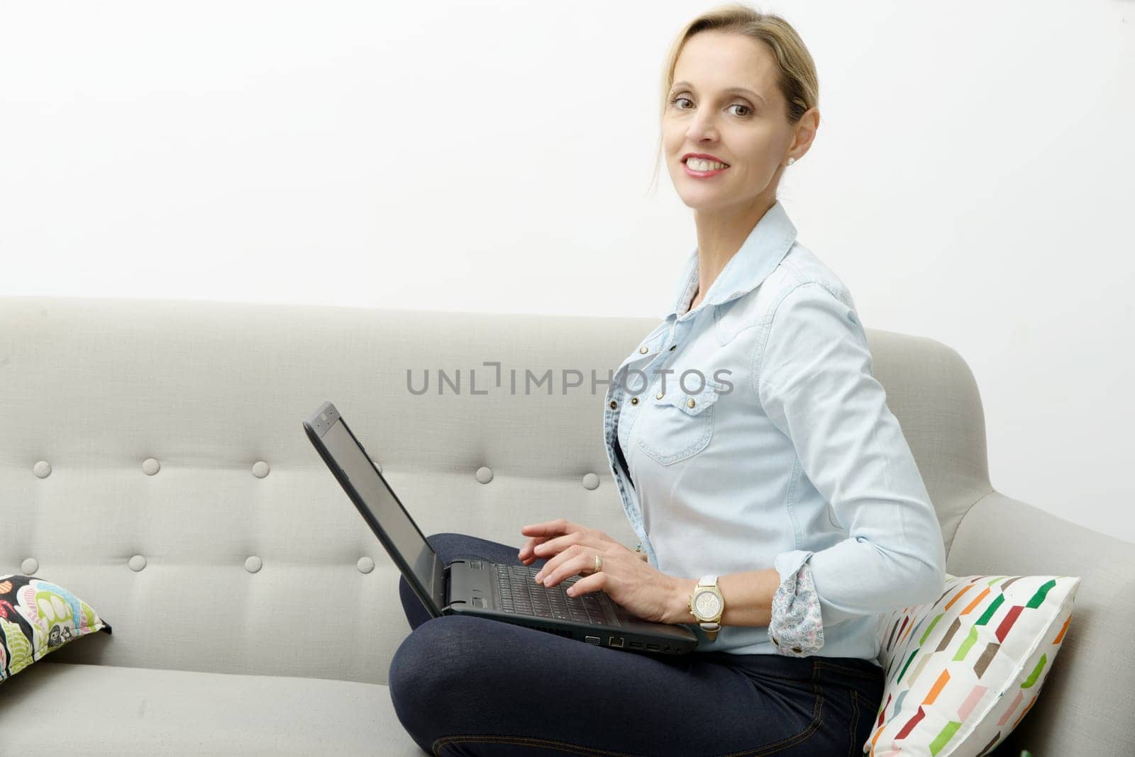 pretty young blonde woman uses a laptop in the sofa