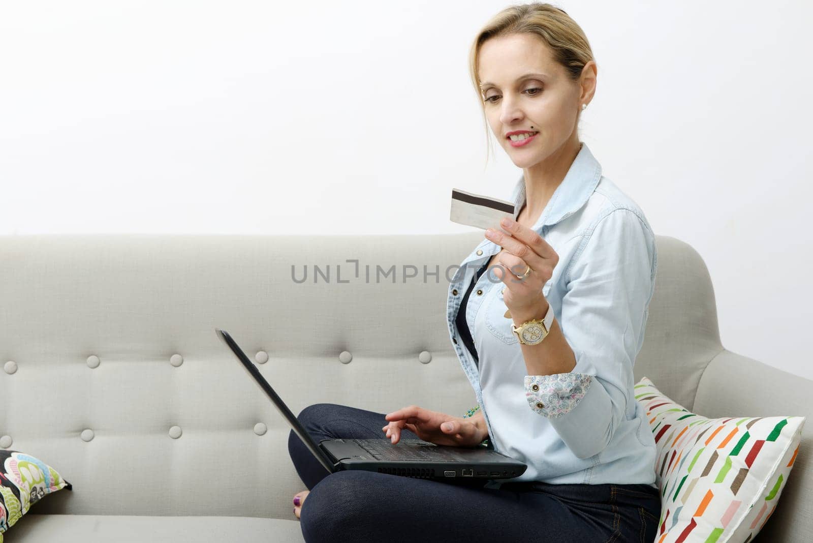 smiling woman shopping online with credit card and laptop.