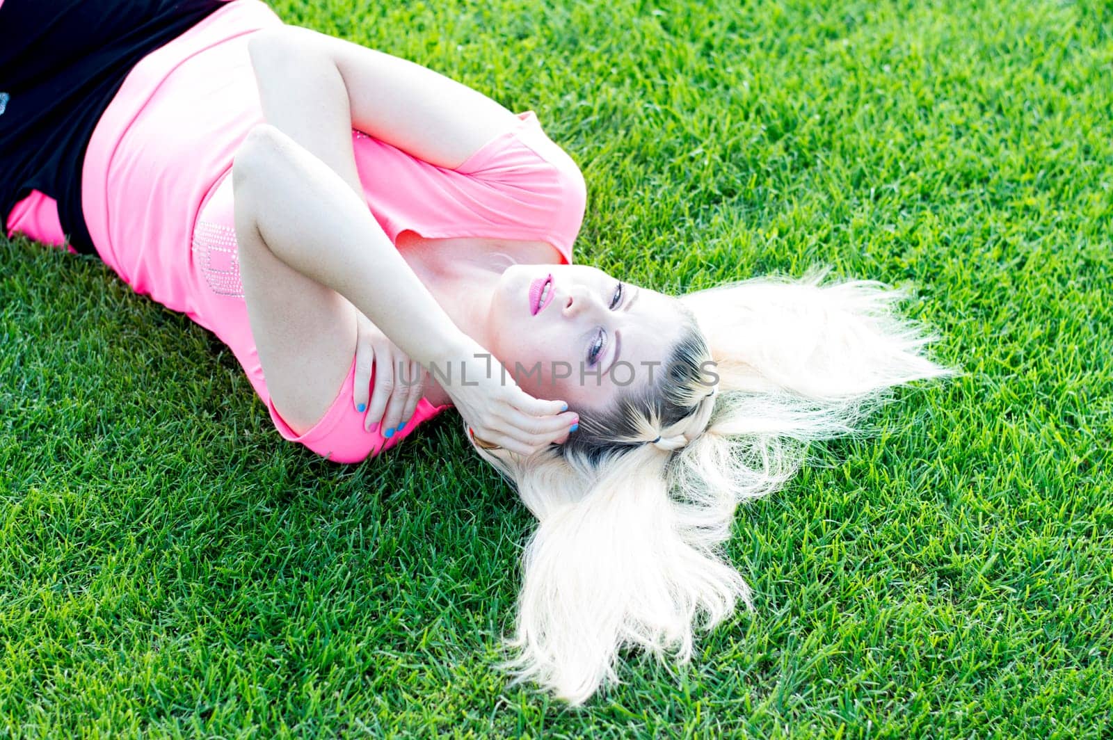 the blonde's portrait with a flowing hair lying the football field, a subject beautiful women, sport, events