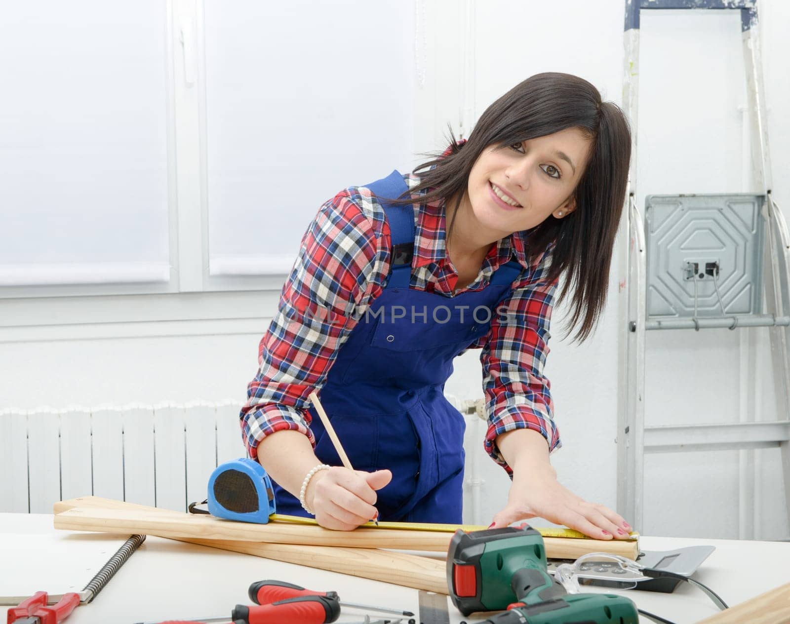 pretty young  woman builder measuring a plank of wood
