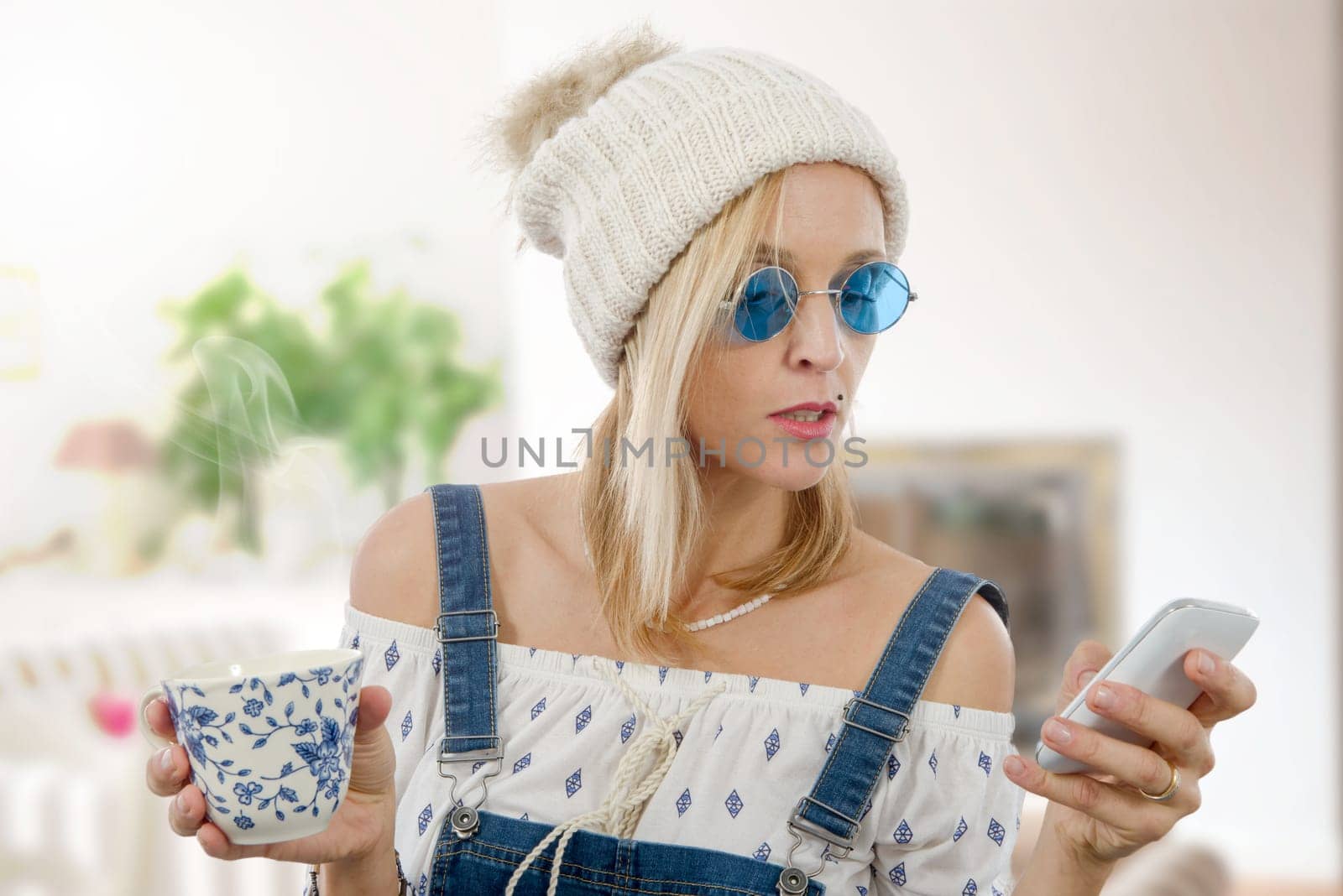 beautiful blond woman with a cup of tea and phone