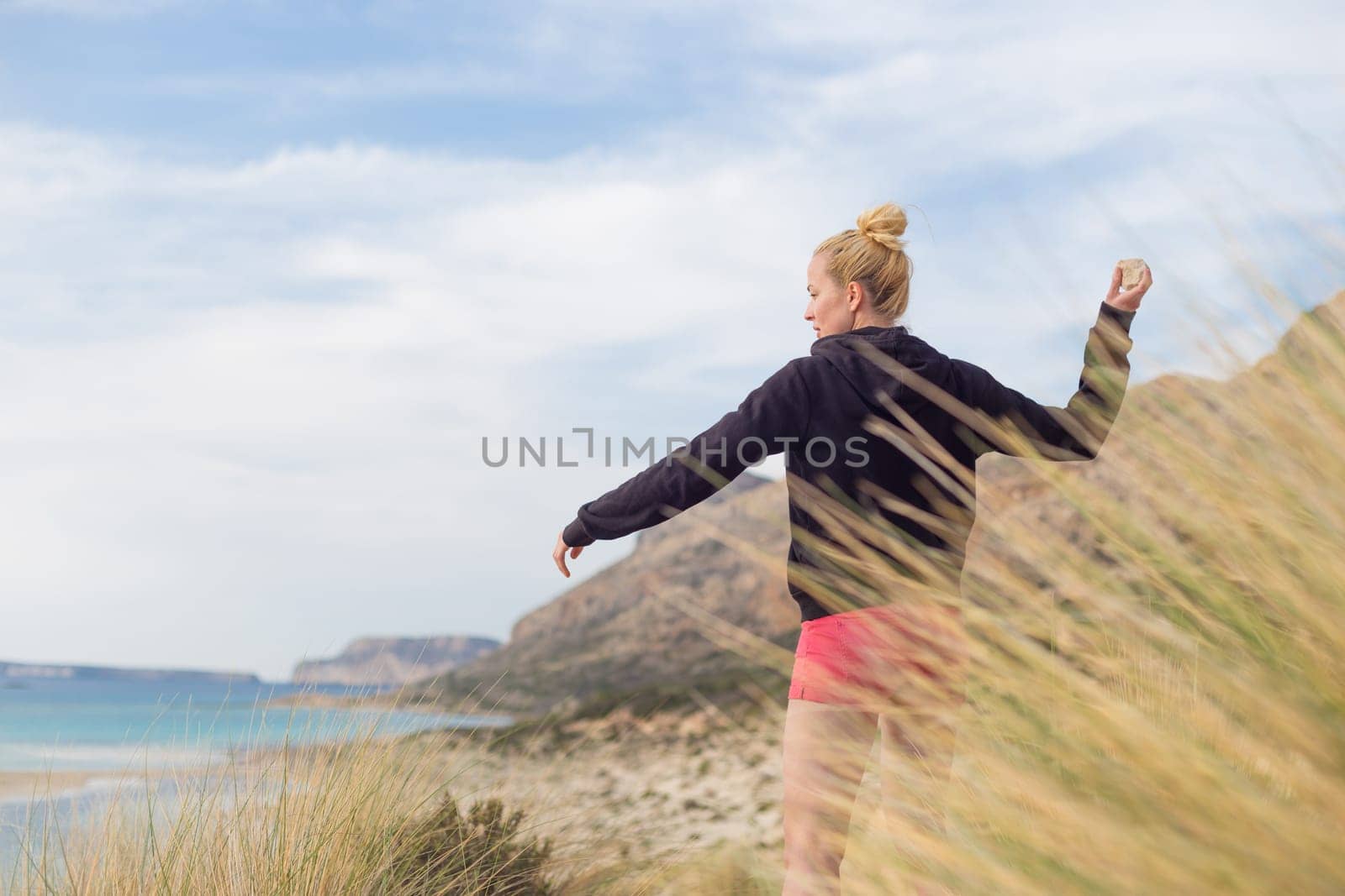 Woman, arms crossed, feeling chilled, enjoying last autumn sun, an beautiful Balos beach. Concept of vacations, freedom, happiness, enjoyment and well being.