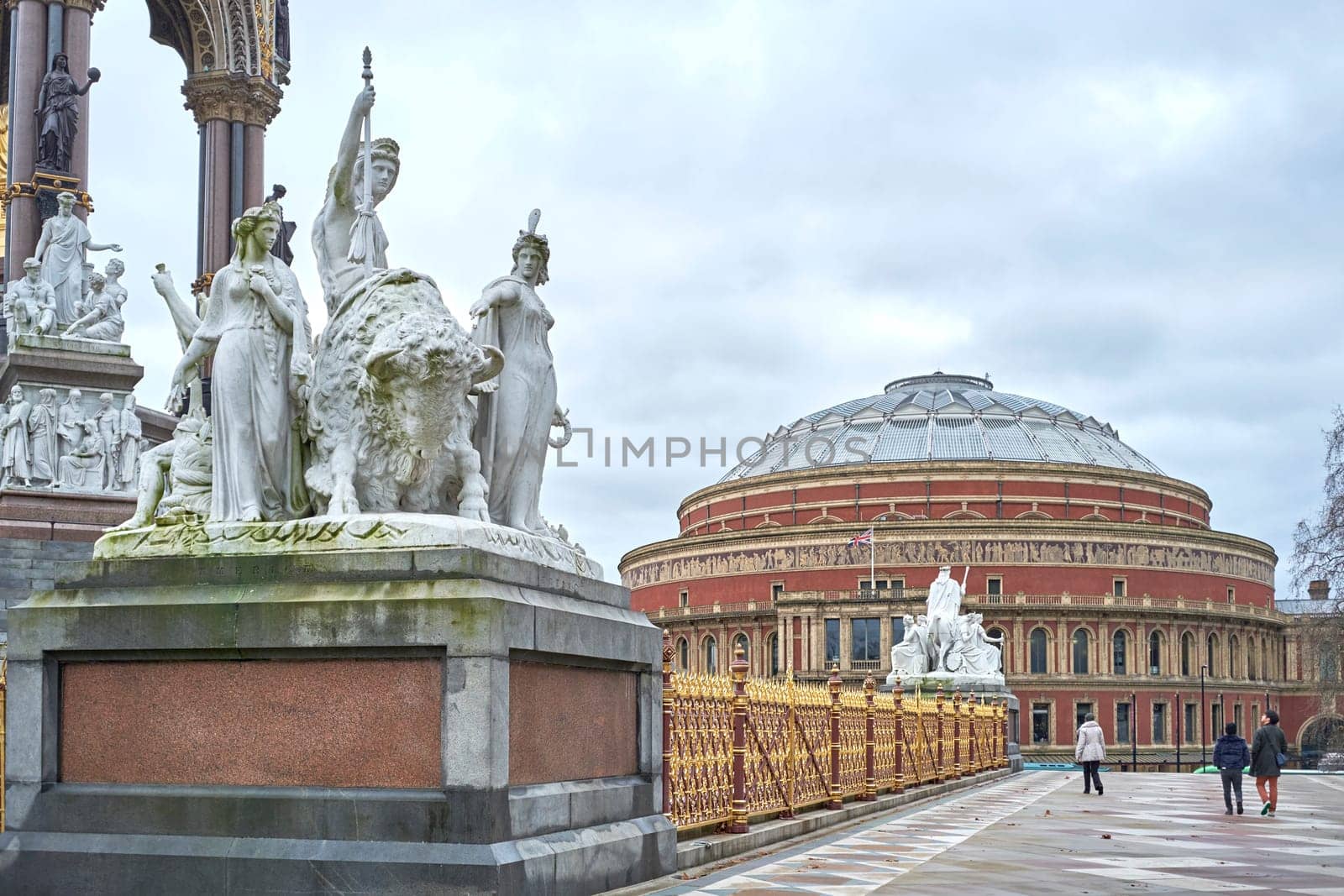 LONDON, UK - DECEMBER 17: Detail of Albert Memorial statue with people walking by and Royal Albert Hall in the background, in Kensington Gardens. December 17, 2014 in London.