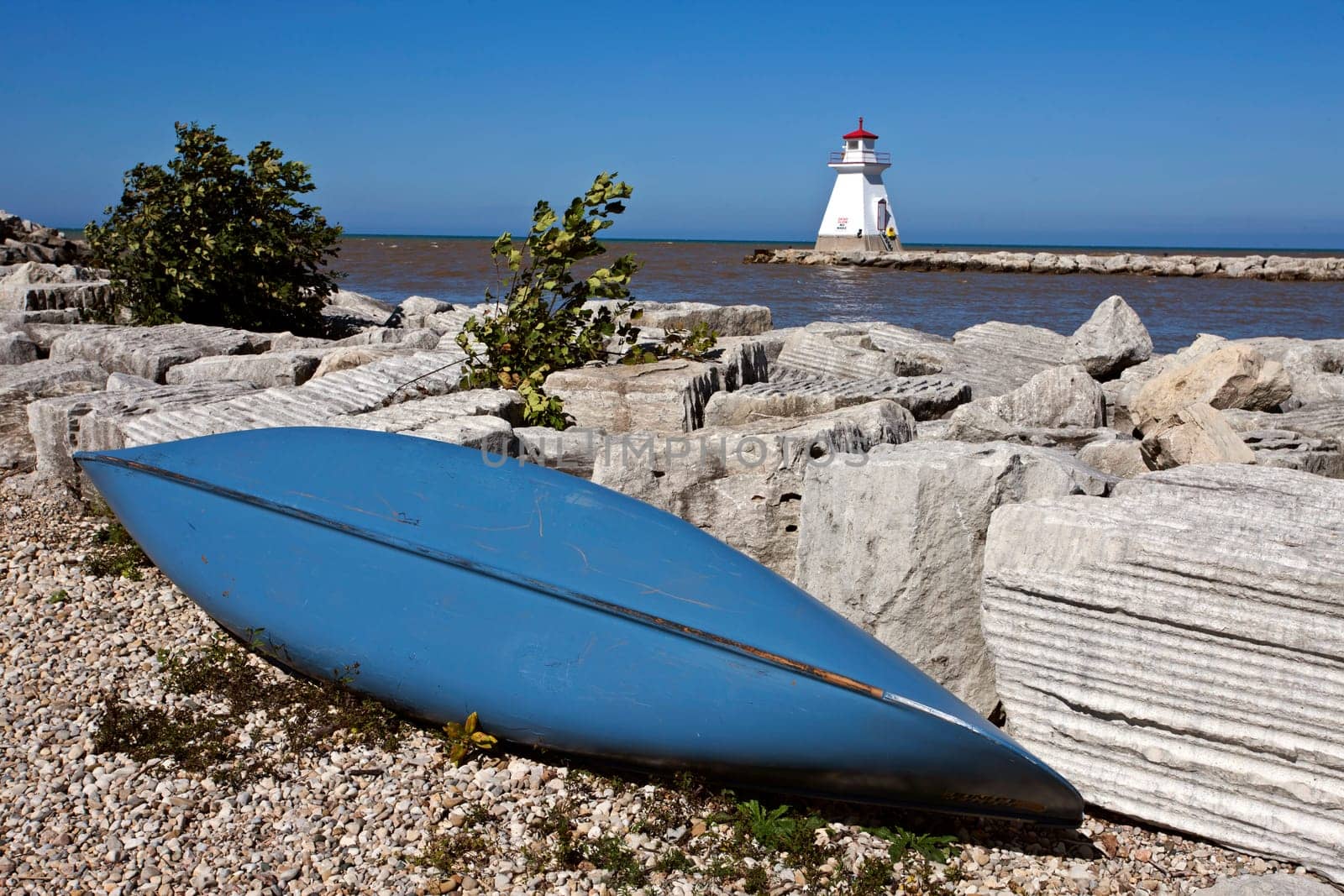 Lighthouse on Lake Huron rocks and blue canoe