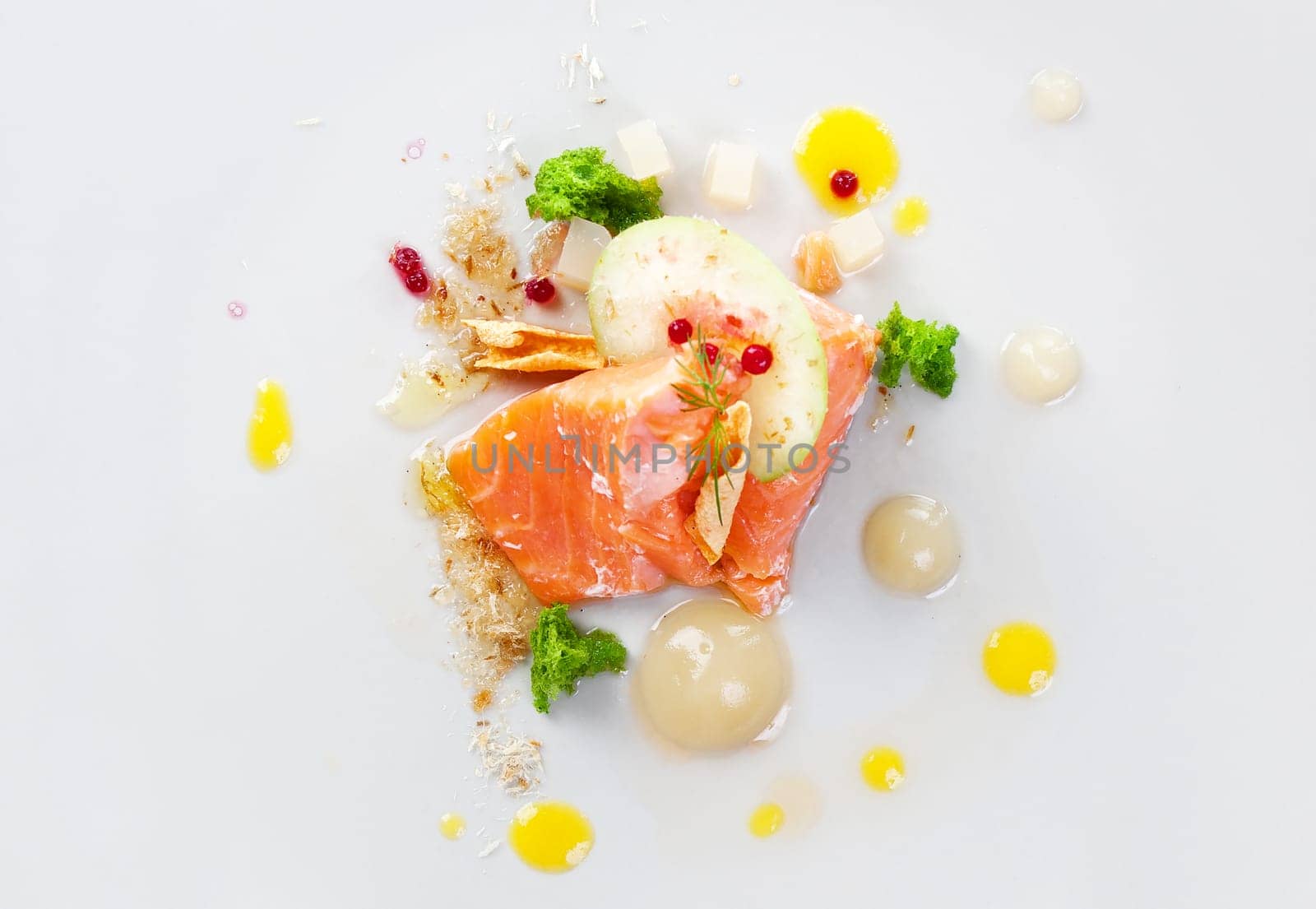 Molecular modern cuisine red fish in a dish with beautiful garnish close up. Isolated