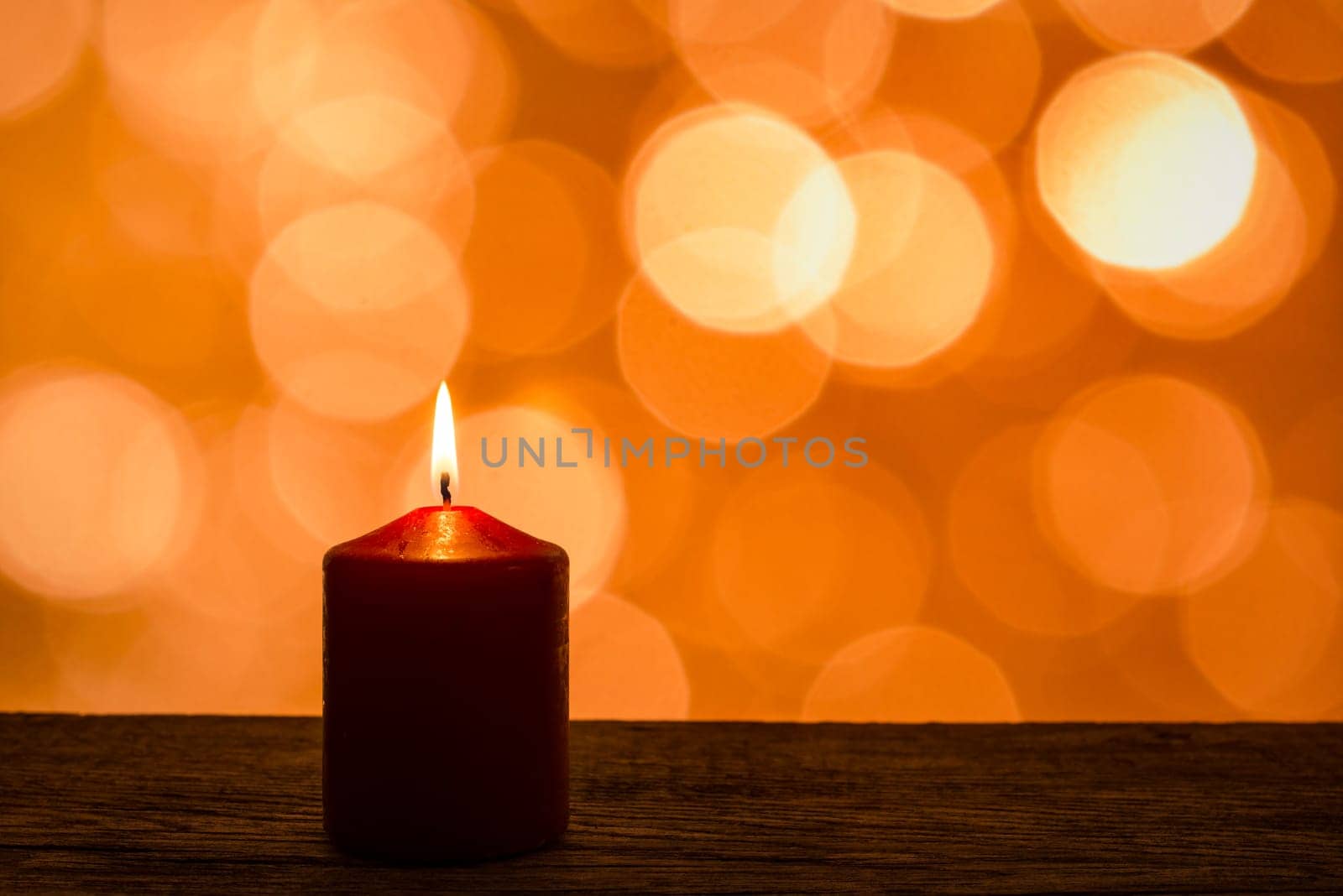 Candle with flame and lights as bokeh in the background