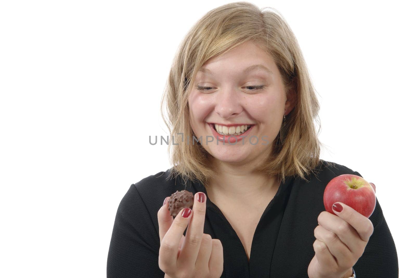 smiling young woman hesitating between a chocolate and an apple