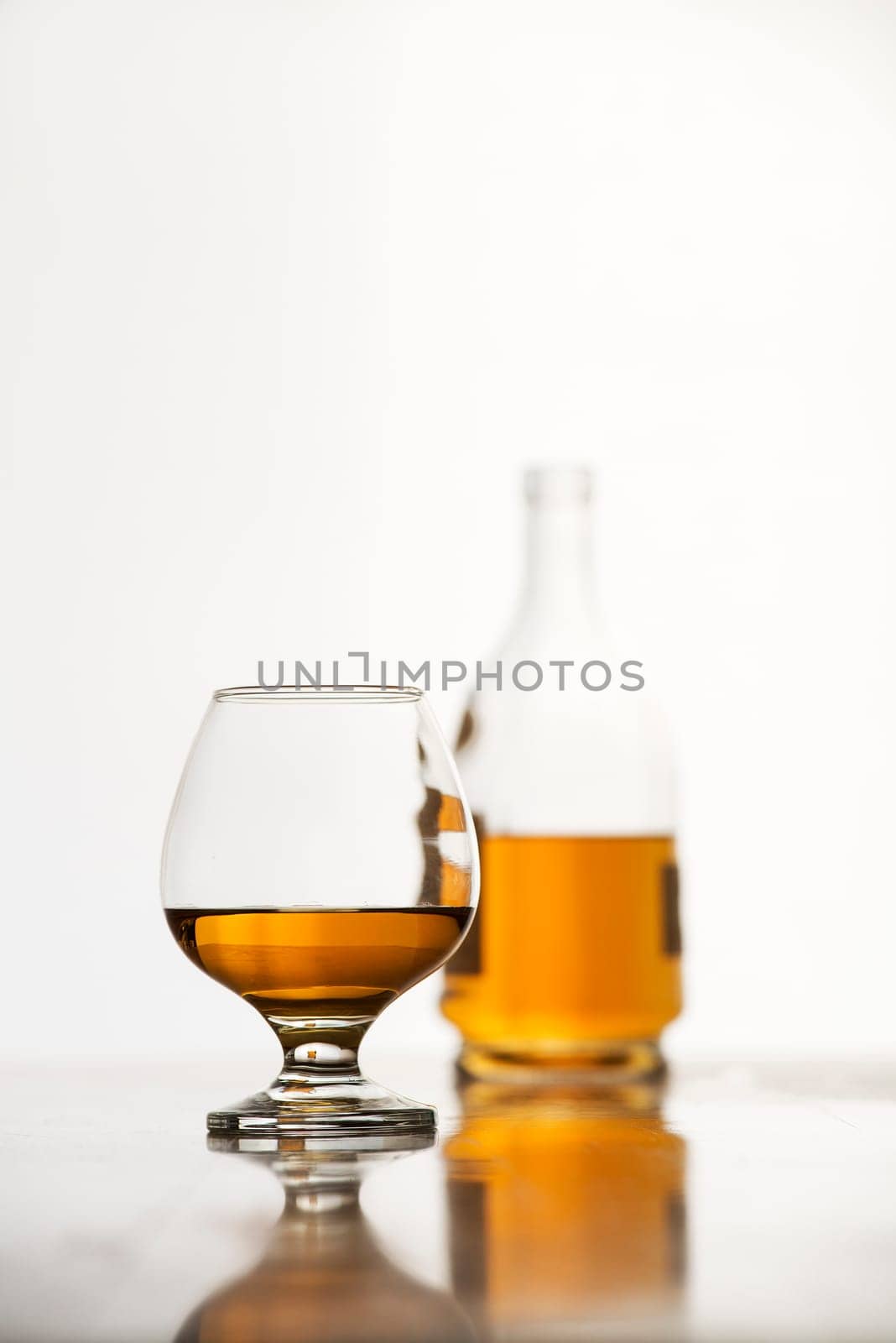 Cognac in glass with bottle on white background