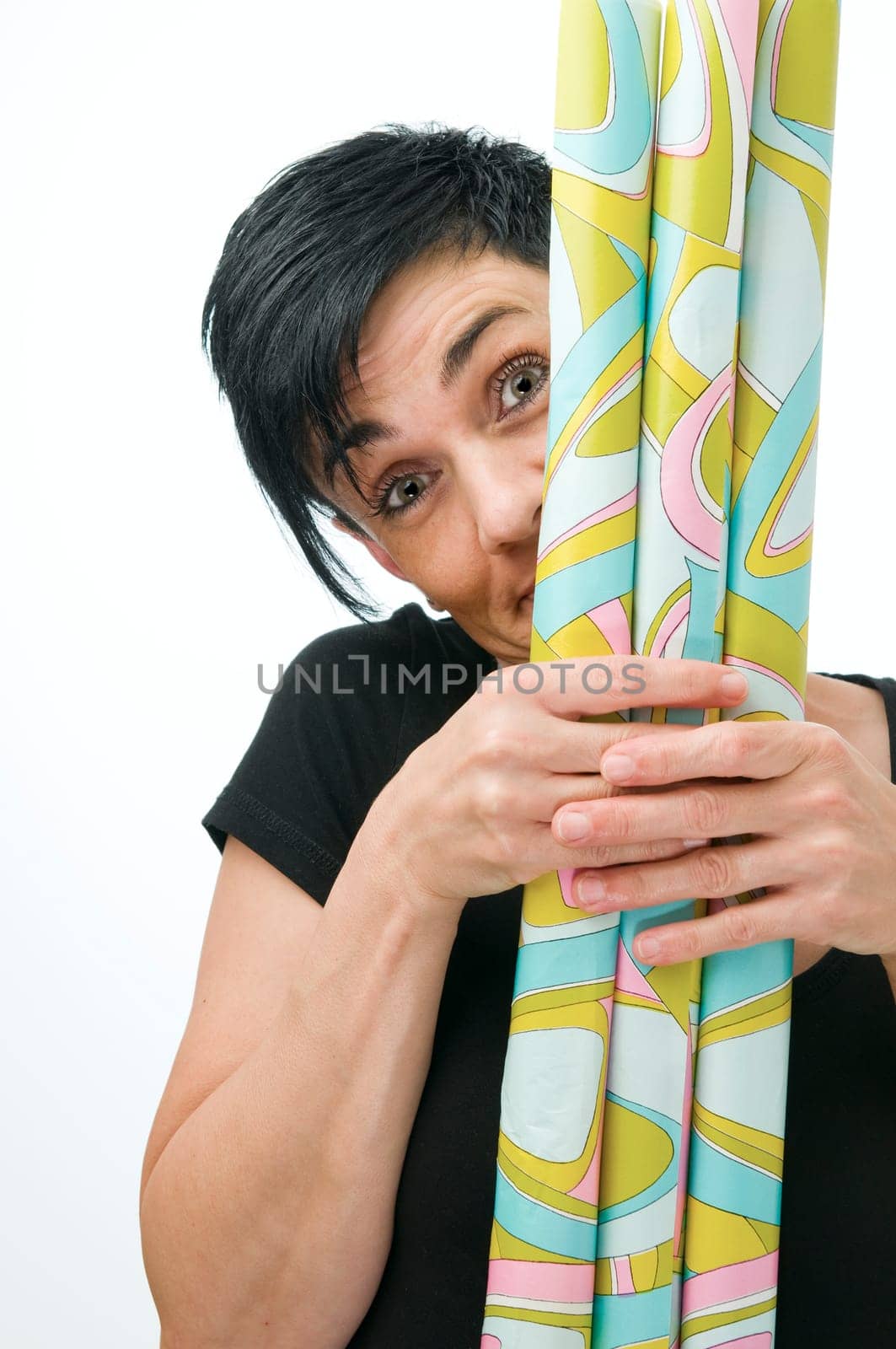 Upper body view of a middle-aged woman hiding behind wrapping paper rolls against a white background.