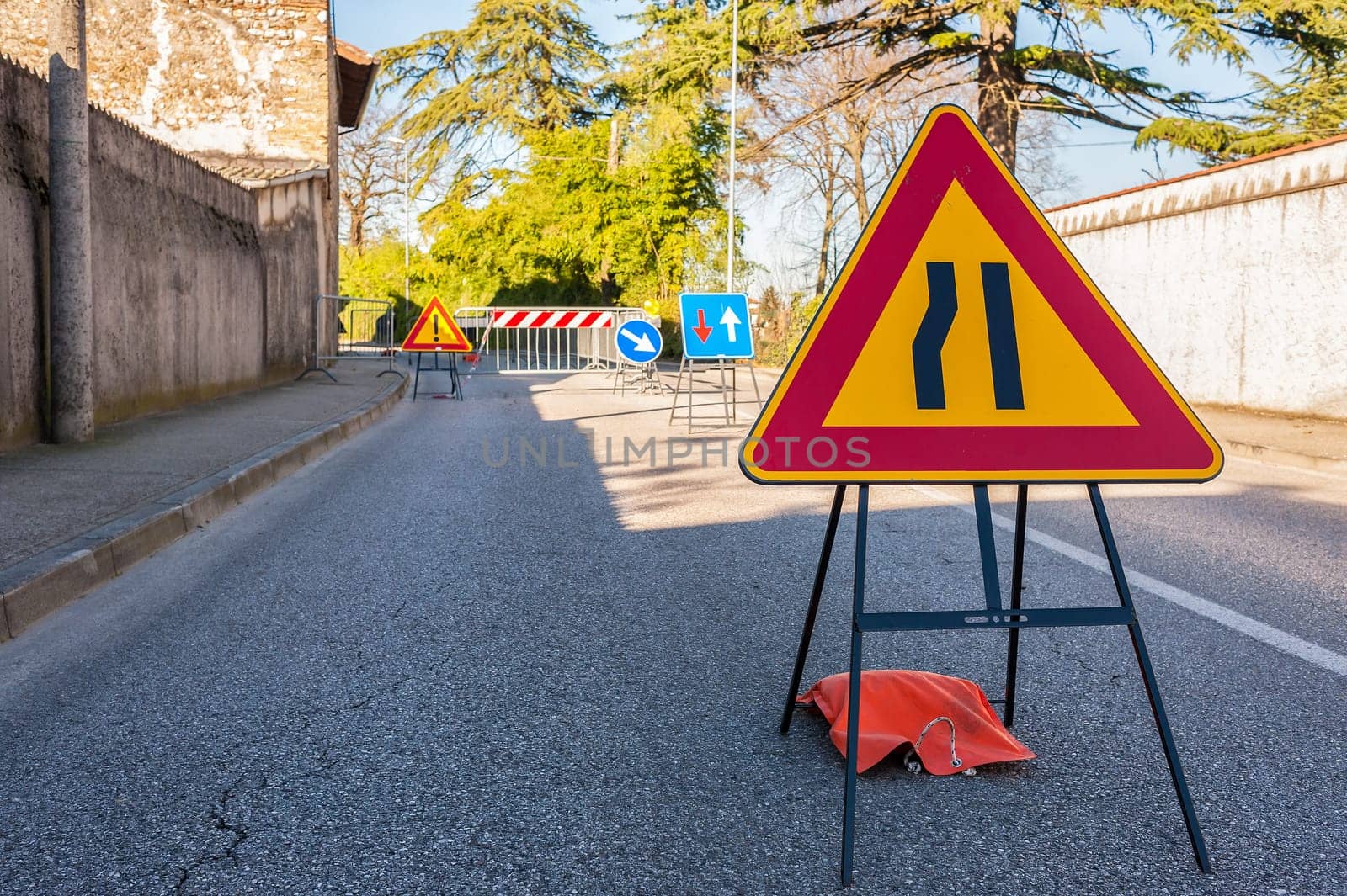 Road sign lane narrowing. In the background, blurred a roadworks site.