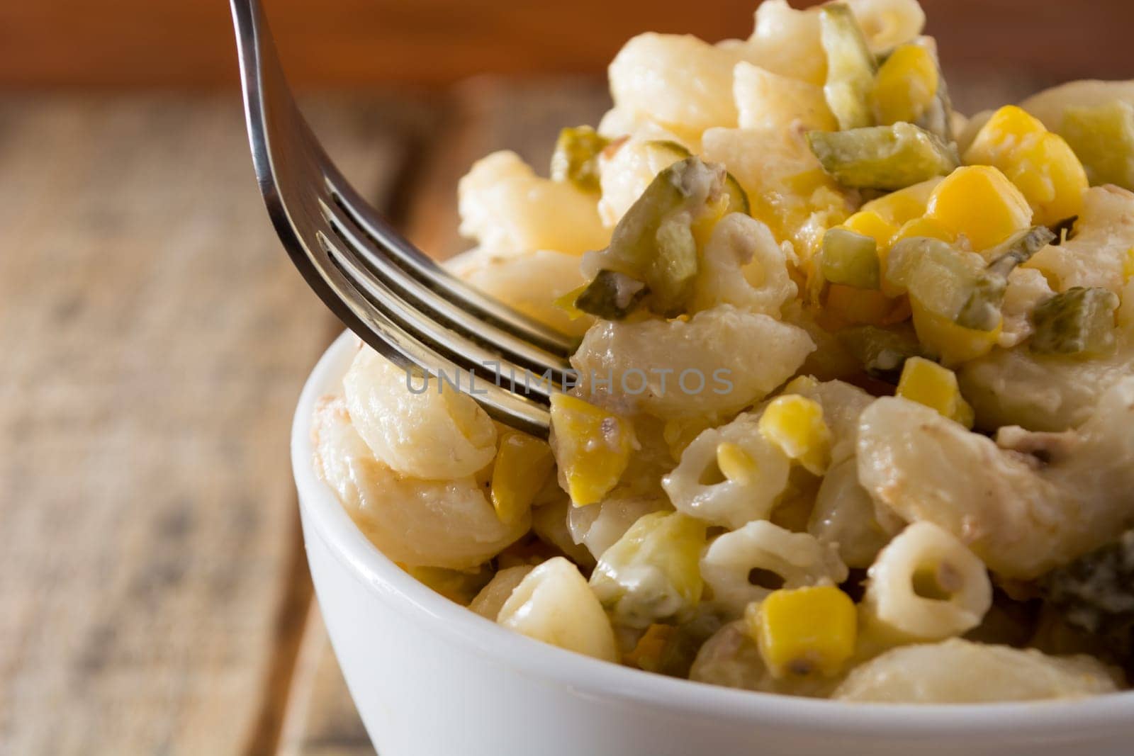 Close up of a fork and salad with pasta, yellow corn and Italian seasonings.