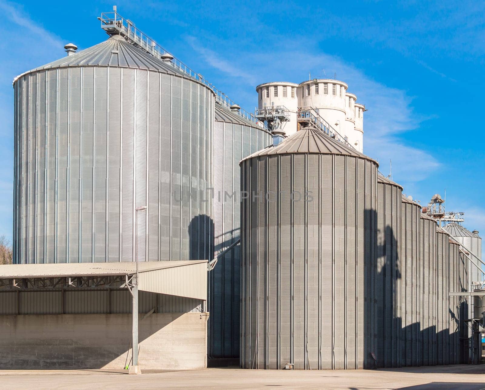 Agricultural Silo. Building Exterior.  Storage and drying of grains, wheat, corn, soy,  against the blue sky with clouds