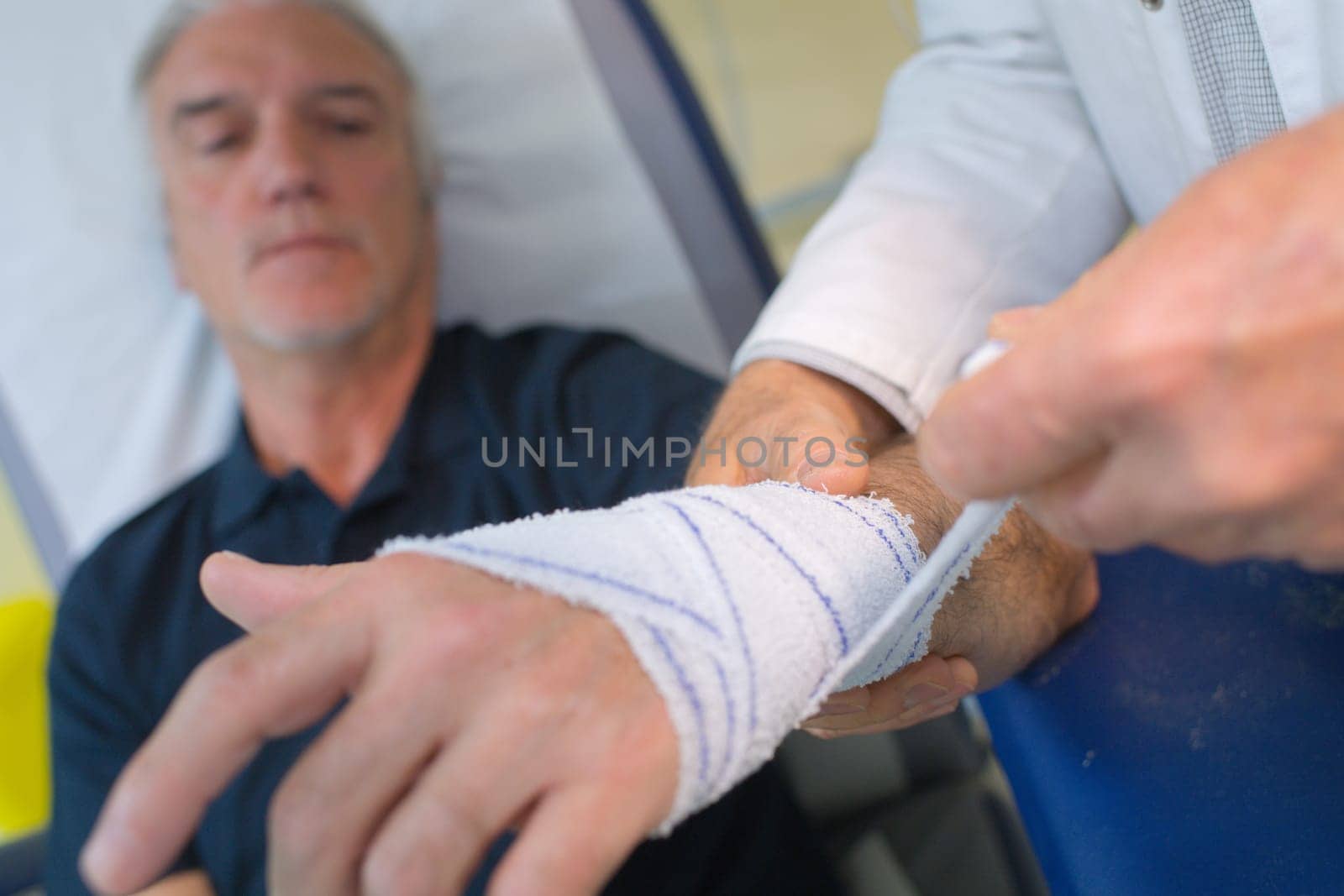 doctor bandaging his patient hand in medical office