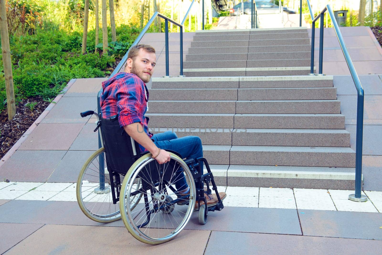 young disabled man in wheelchair in front of stairs
