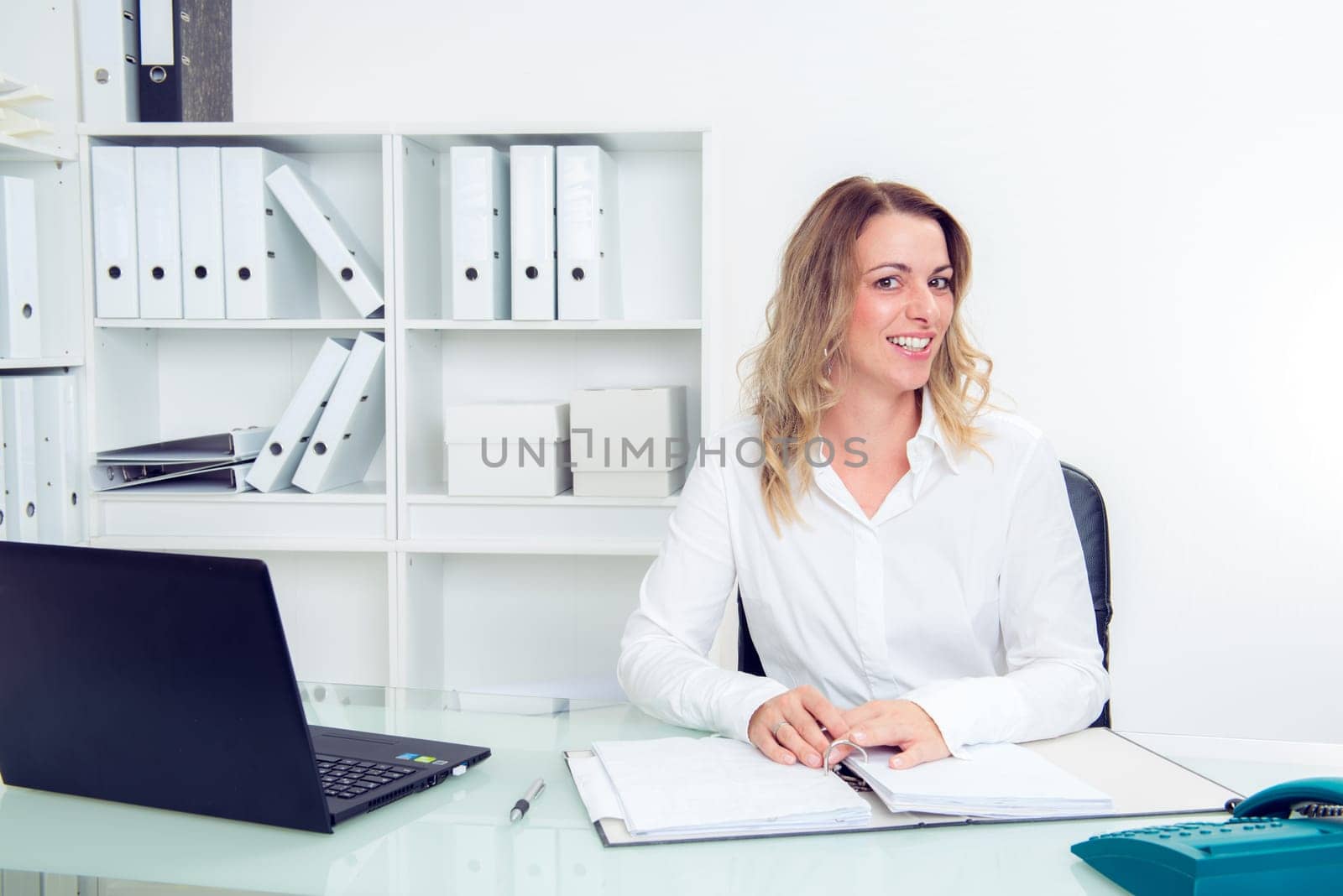 young blond businesswoman in the office smiling in to the camera