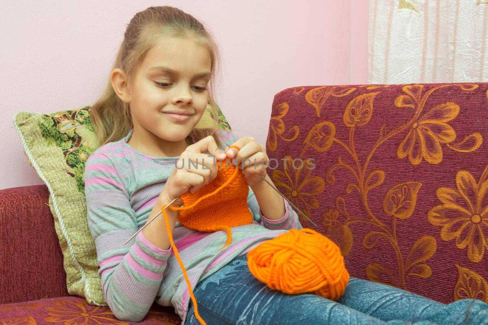 Girl lying on the couch and knits on spokes